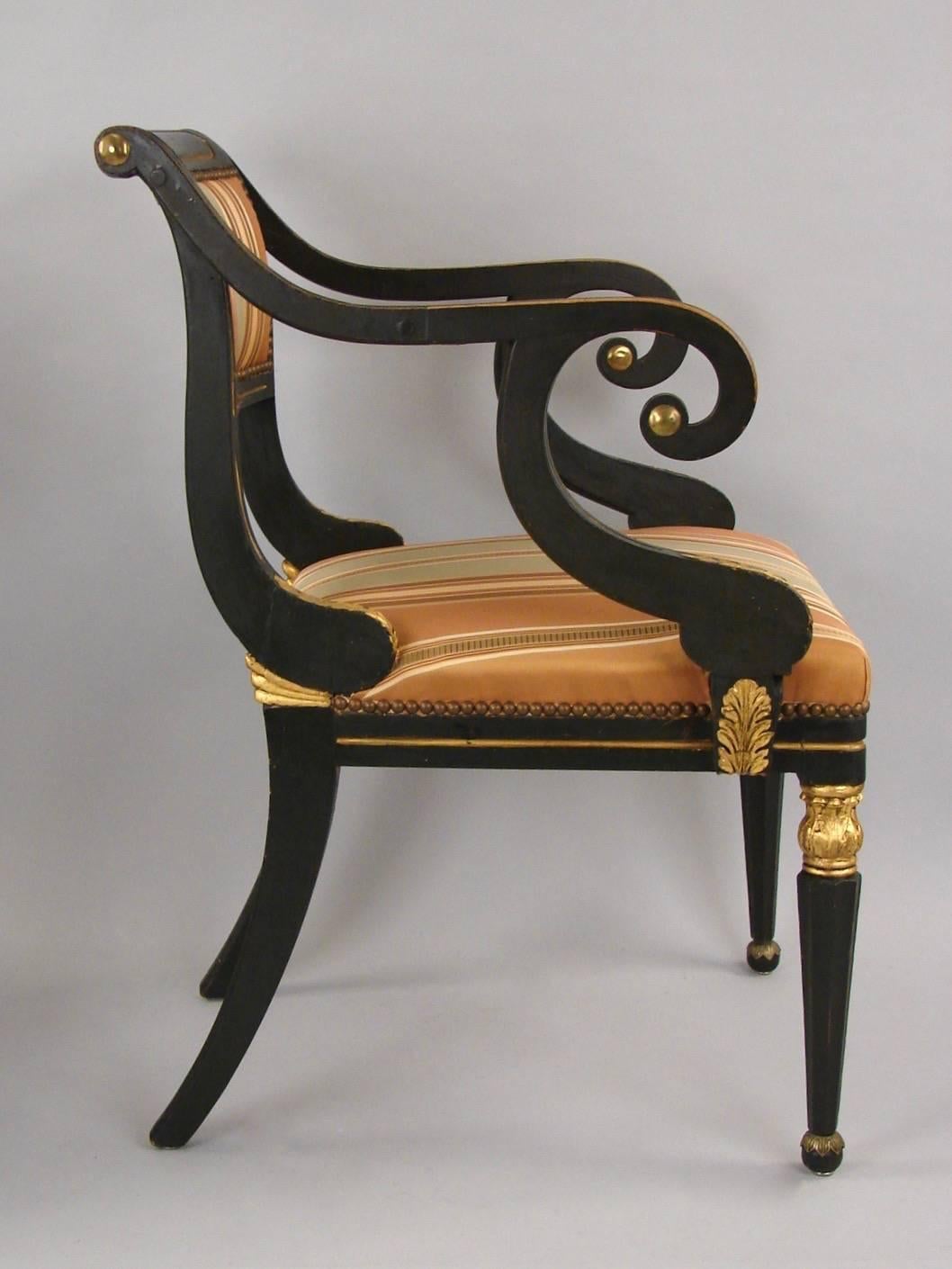 A pair of Regency green painted and parcel-gilt open armchairs, the scrolled arms over faceted front legs with acanthus leaf details, circa 1815. Now upholstered in striped silk fabric.

 
