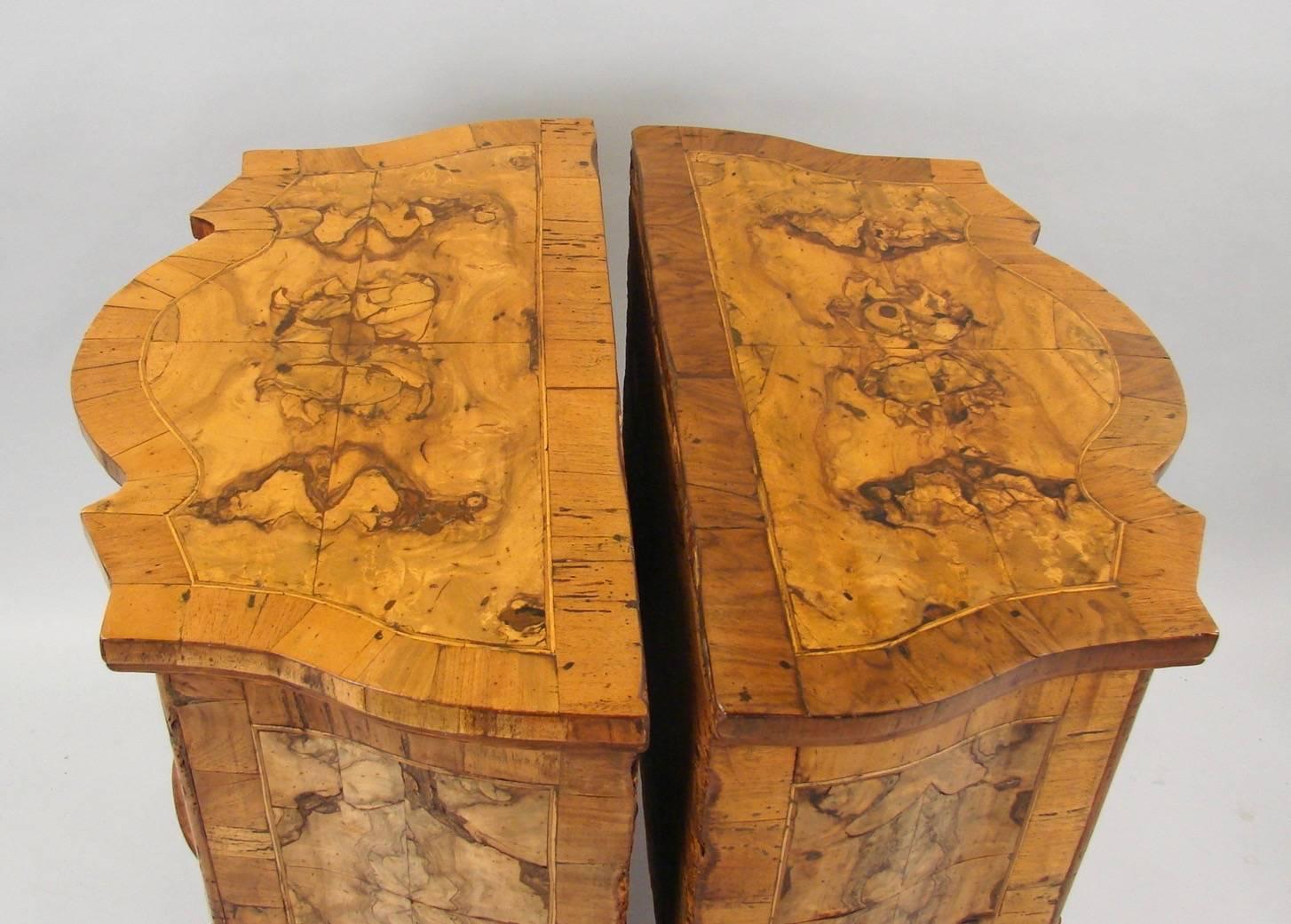 A pretty pair of Italian Rococo style figured walnut comodini of serpentine form, each with shaped tops above two drawers, raised on short carved cabriole legs, 
with crossbanding throughout. Composed of antique elements.