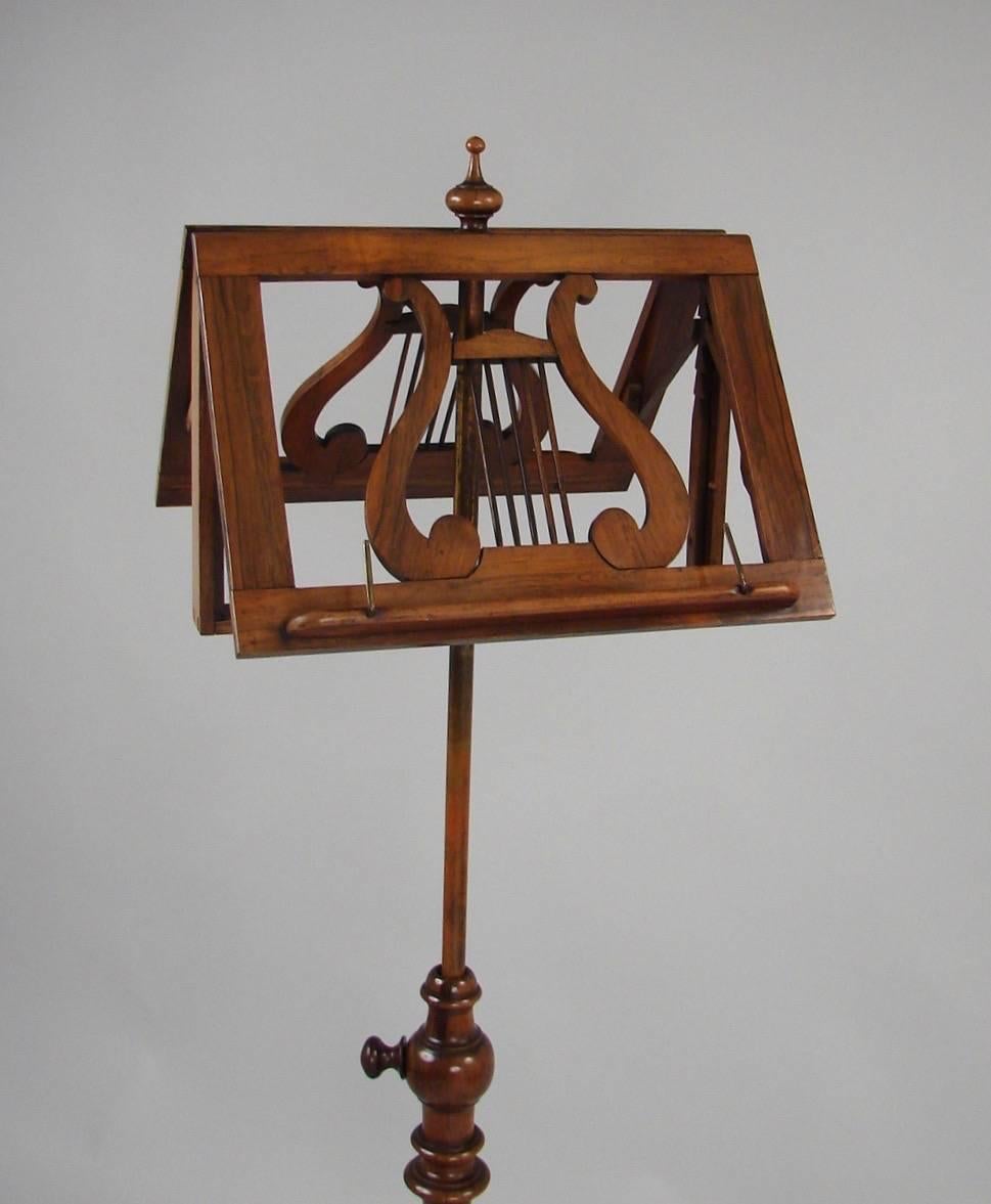 A pretty English rosewood duet music stand, each side with adjustable ratchet mechanism decorated with brass inset lyres, resting on a turned standard ending in a carved tripod base with down swept feet, circa 1870.