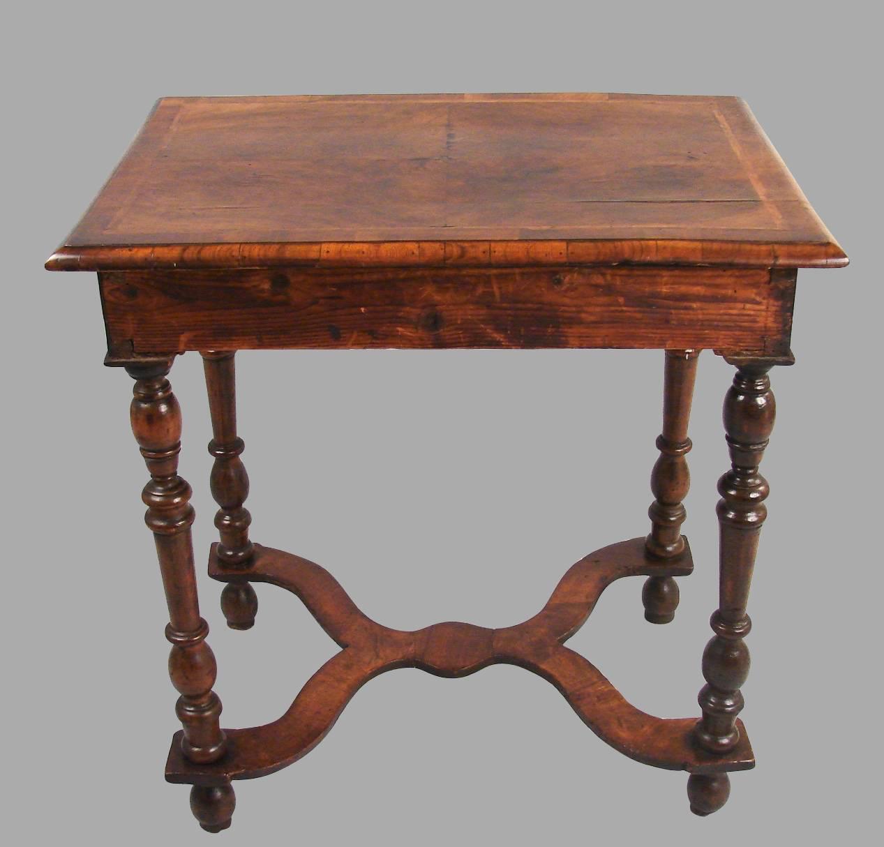 A lovely William and Mary period walnut occasional table, the quarter veneered crossbanded top with chevron inlay above a single drawer supported on well-turned legs connected by a wavy stretcher over bun feet, circa 1690.