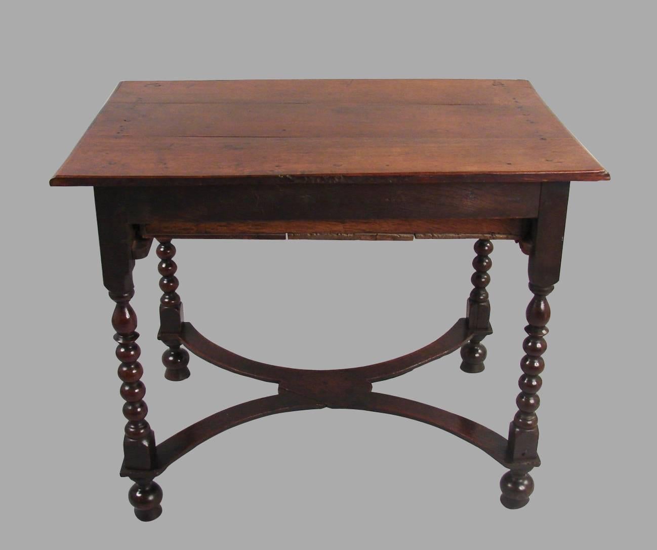 An oak William and Mary period table, the molded overhanging top above a single long drawer supported on bobbin turned legs joined by a flat double crinoline stretcher ending in bun feet.