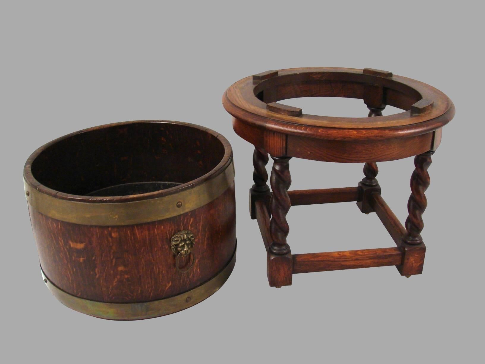 An English Provincial oak brass bound jardiniere with lion's head handles mounted on a circular Stand with rope twist legs joined by a box stretcher ending in block feet. Made and labeled by R.A. Lister & Co. Dursley, England.