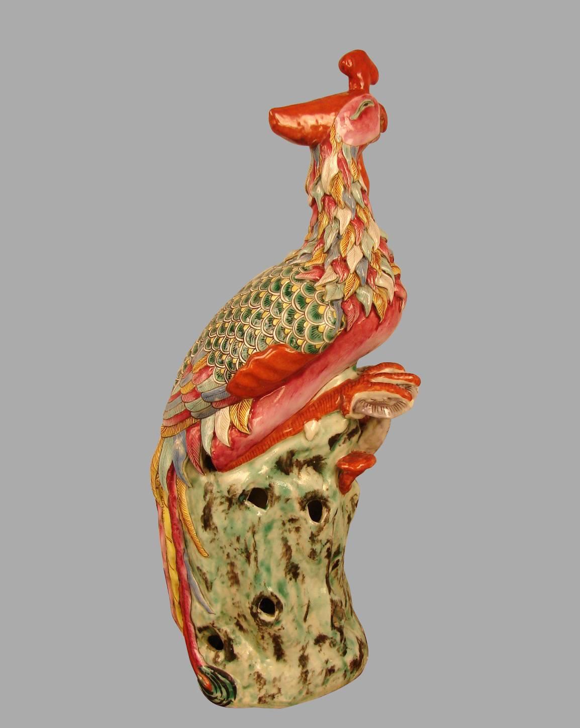 An attractive pair of Chinese export glazed earthenware phoenix birds brightly decorated overall in coral, green, and light brown depicting perched birds on stumps, late Qing dynasty.