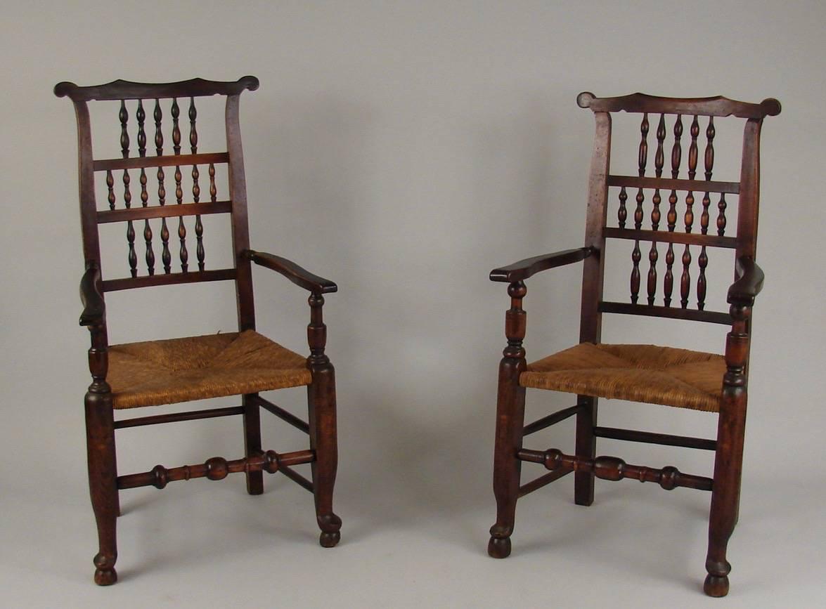 A set of English elm provincial dining chairs with rush seats, each with spindle backs and turned stretches, the armchairs with minor variations in height, circa 1880-1900.