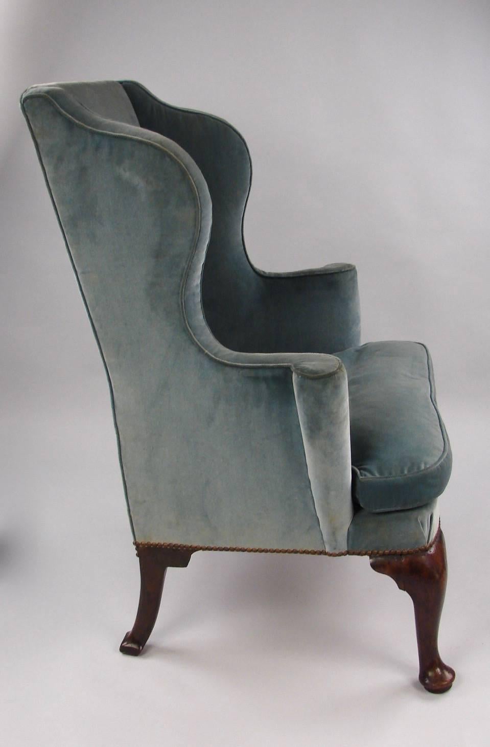 A good English George II period walnut wing armchair of elegant small size with cabriole front legs and canted rear legs, now upholstered in blue velvet with a cushion seat, circa 1750.