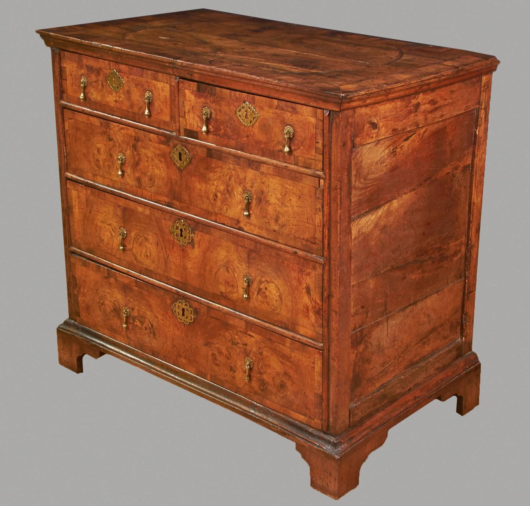A fine William and Mary walnut chest with paneled sides, the inlaid cross-banded and quarter veneered top above two short and three long banded drawers resting on later bracket feet, circa 1690-1700. Excellent old color and patina.