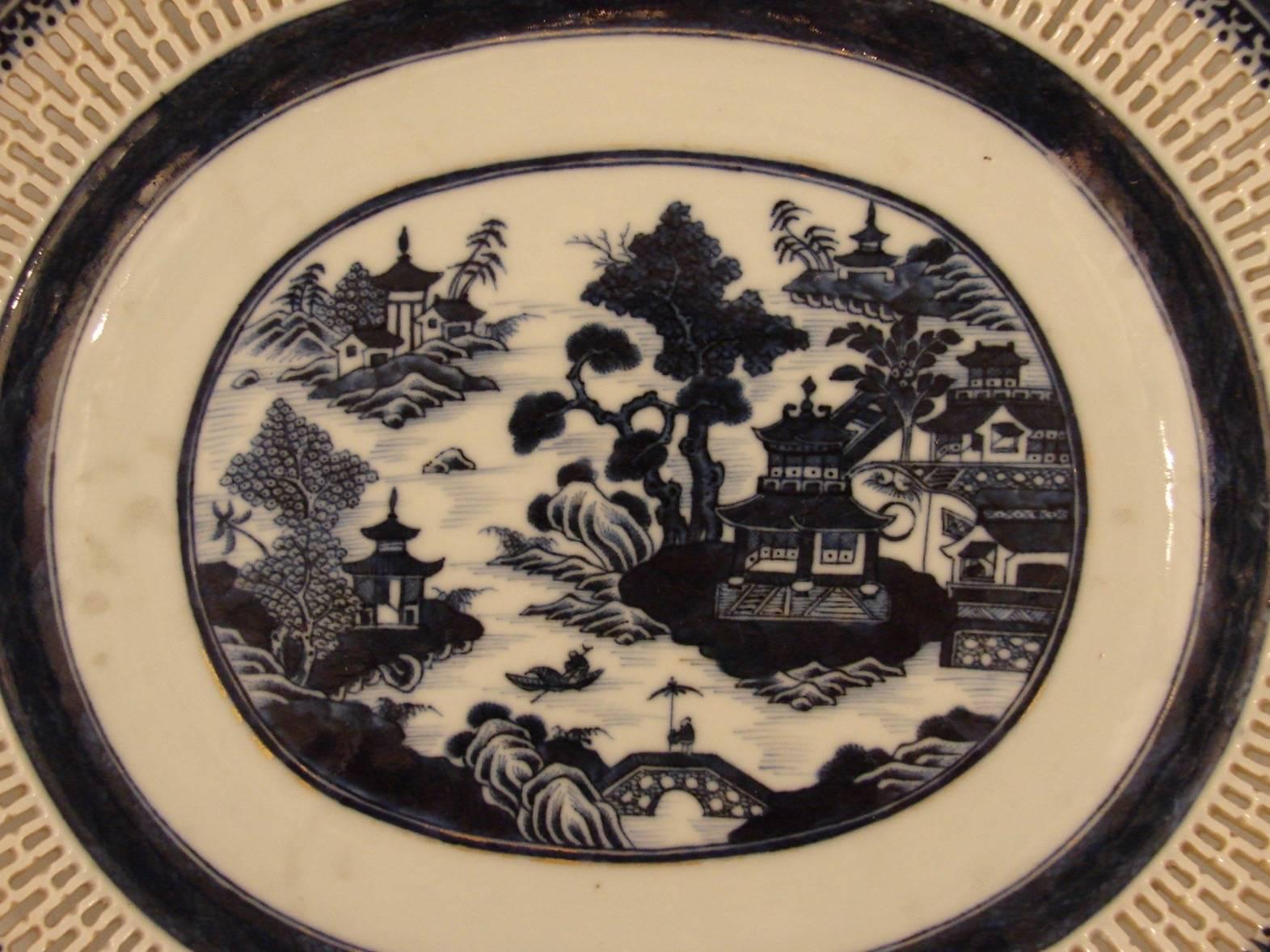 A canton oval platter with a reticulated border depicting a typical river scene with traditional houses, monogrammed on the reverse, circa 1850.