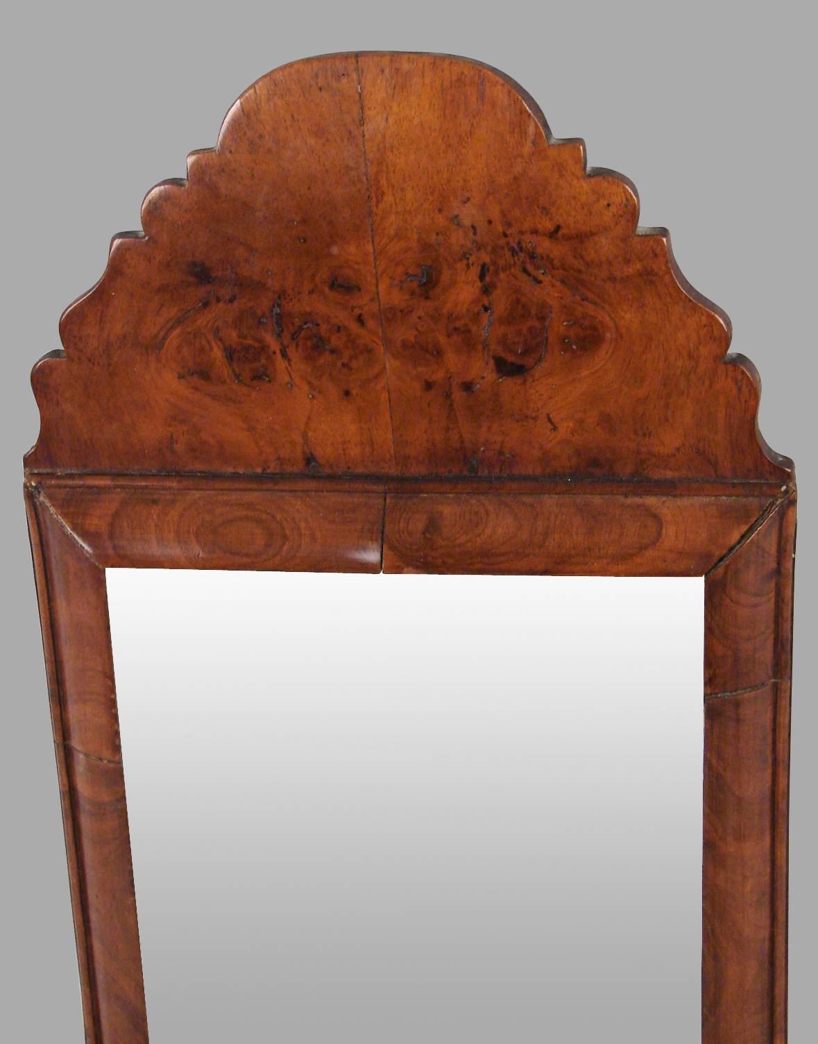 A charming English or Northern European burl walnut mirror of small size with a beveled plate, the shaped crest above a simple molded frame, circa 1750-1800.