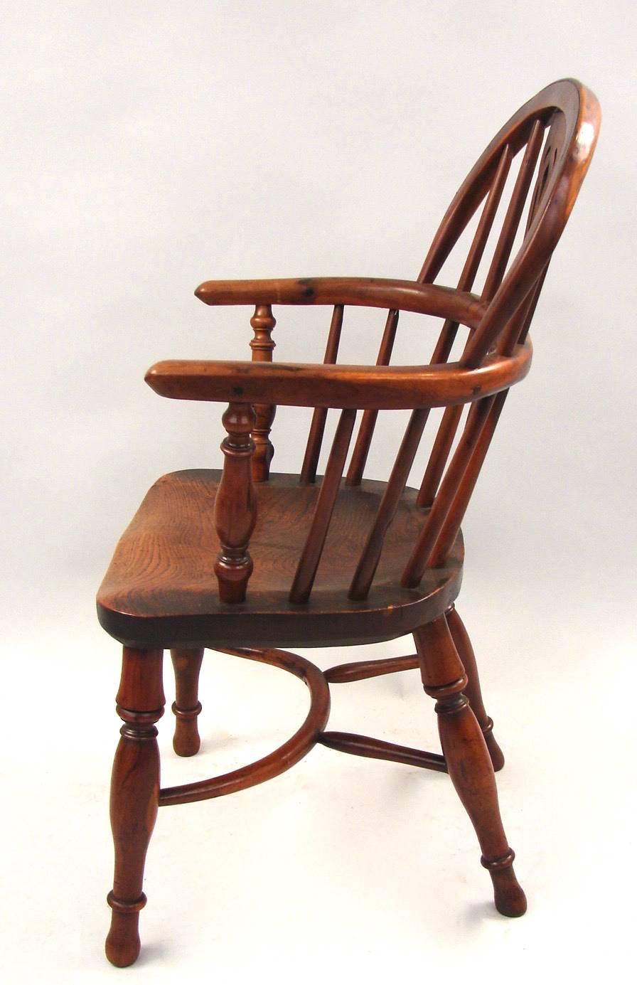 A rare signed English yew wood and elm windsor child's armchair of typical form, stamped on the seat edge Whitworth Gamston, made by John Whitworth, the legs joined by a crinoline stretcher circa 1840-1860.