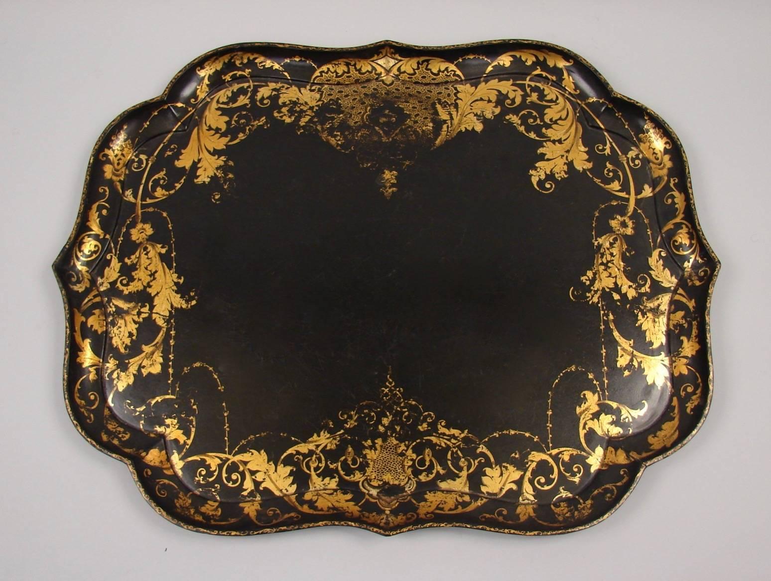 An English Victorian scalloped edge papier mache tray with foliate gilt perimeter decoration now mounted on a faux bamboo custom stand of a later date, 
circa 1860. Repolished.