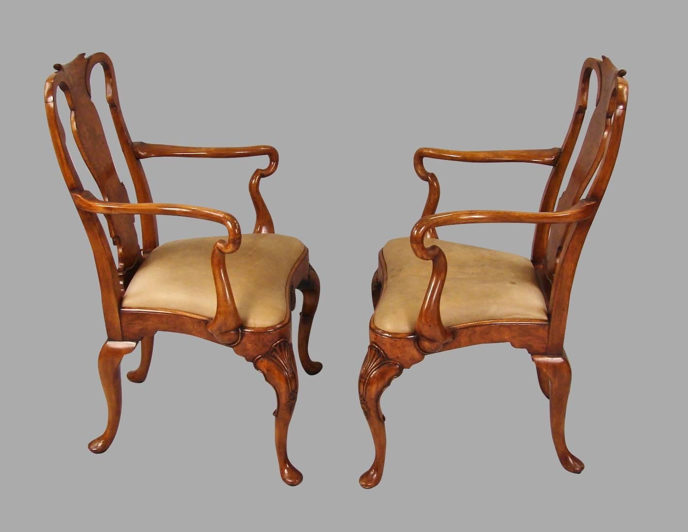 An attractive and substantial set of 12 English Georgian style walnut and burl walnut veneered dining chairs consisting of 10 sides and two-arm chairs, each with a carved burled walnut splat, the drop-in balloon seats upholstered in brown hide,