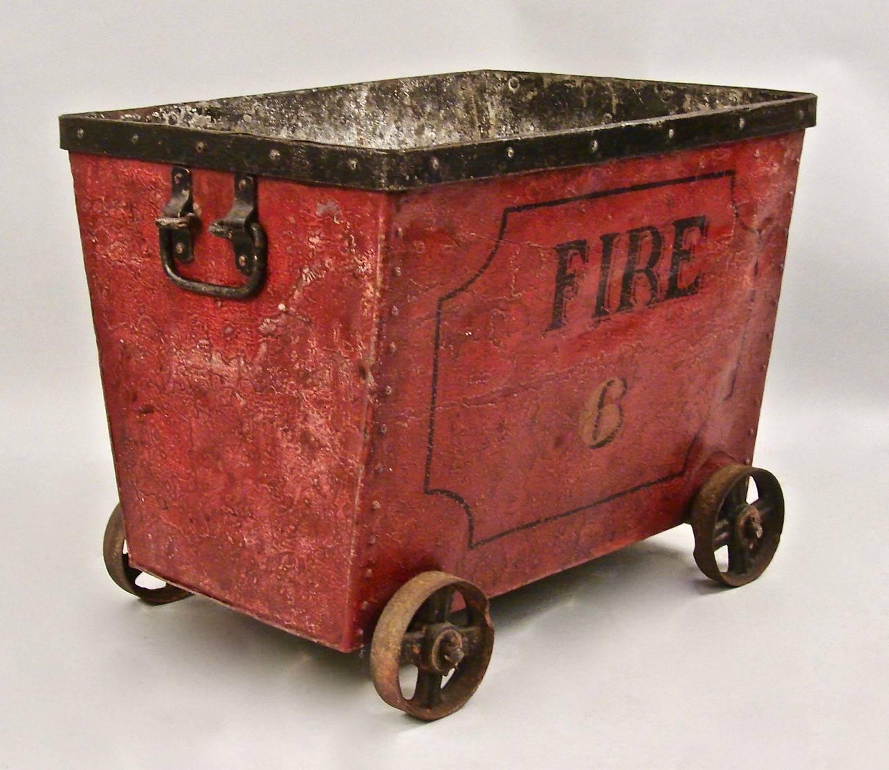 An unusual painted metal cart with rivet construction, the top with a black applied edge, the front stencilled fire six, supported on metal spoked wheels with carry handles on the sides. Wonderful old surface and paint. This may have been used by