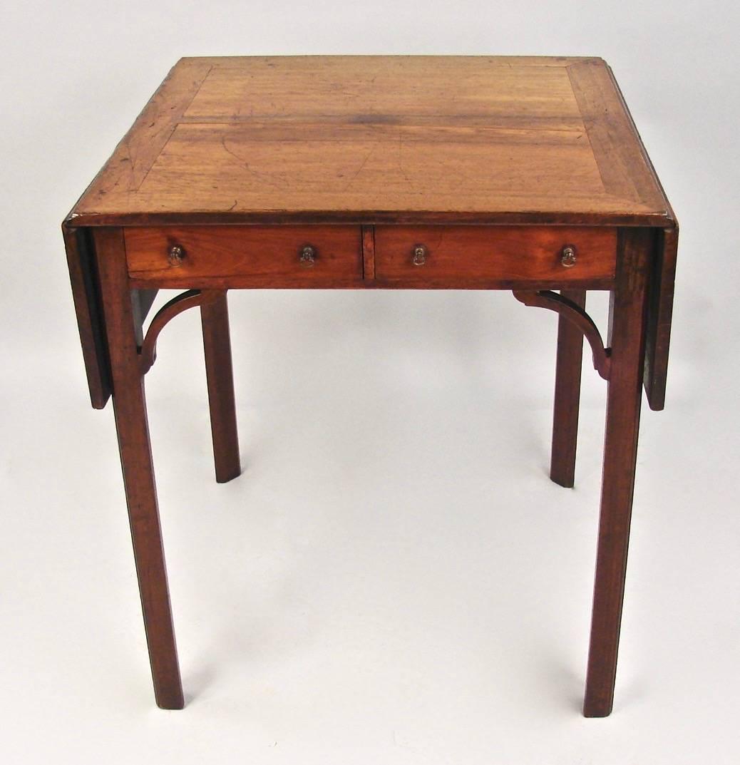 A George III period padouk wood games table, one side fitted with two short small drawers, the other fitted with two long narrow drawers which become a backgammon board, the top with two drop leaves, resting on chamfered legs headed with corner