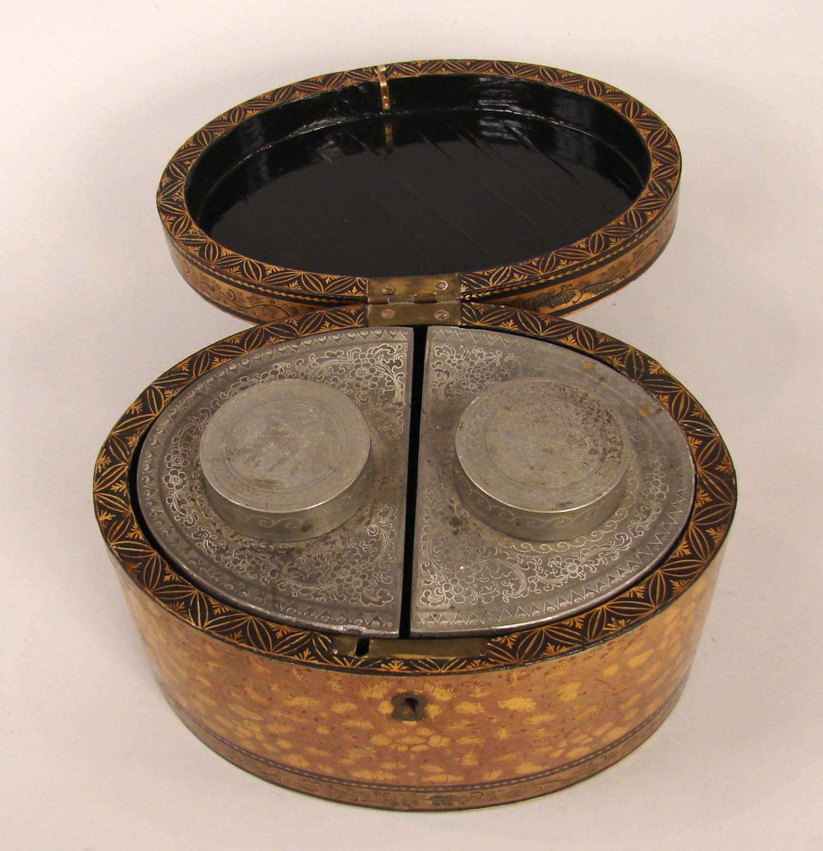 An attractive Chinese export gilt lacquer oval tea caddy decorated overall with black and gilt foliate designs, the interior with two engraved pewter canisters,
the top with stylized initials, circa 1825. Restored.