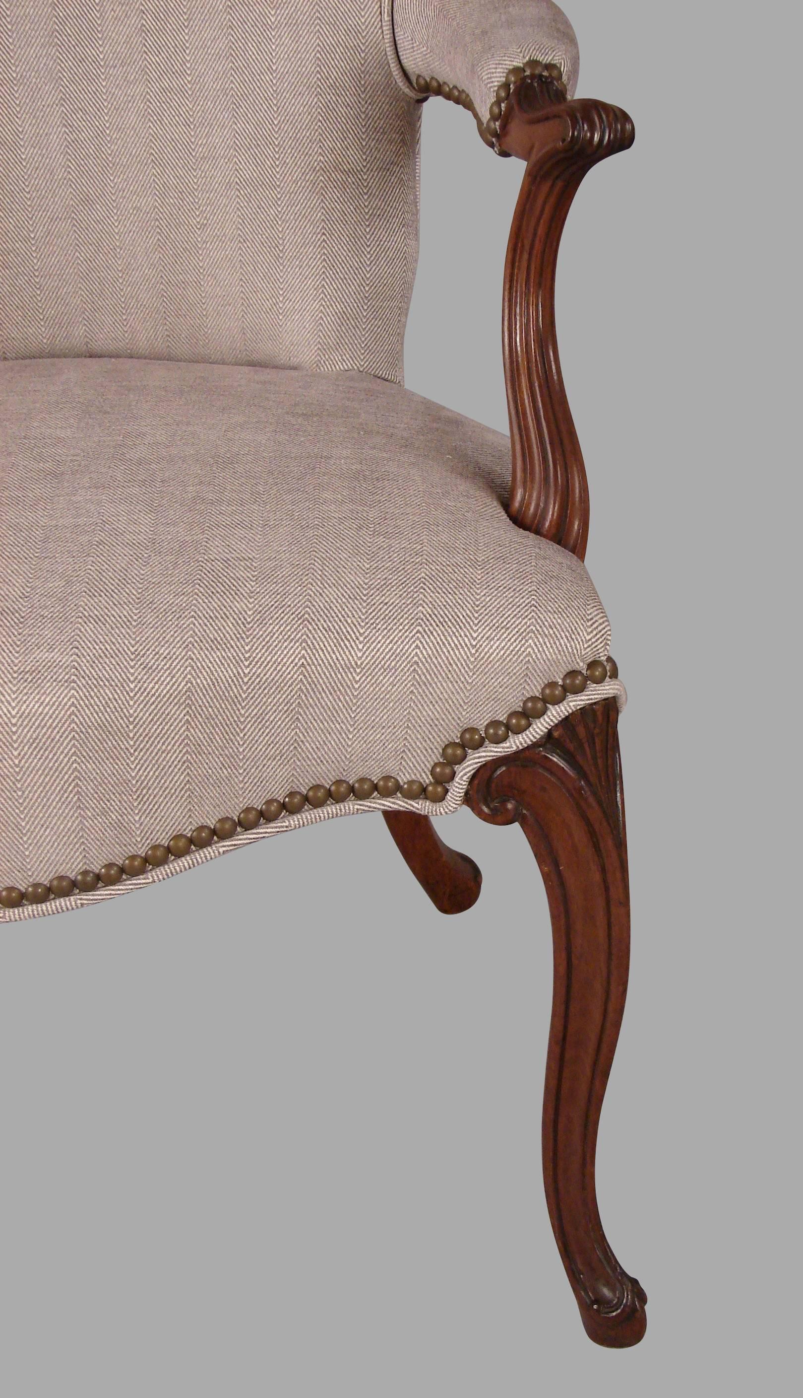 A near pair of English mahogany Hepplewhite style armchairs in the French taste, each with fluted and tapered arms and cabriole legs. Newly upholstered in a contemporary herringbone fabric with nailhead trim.