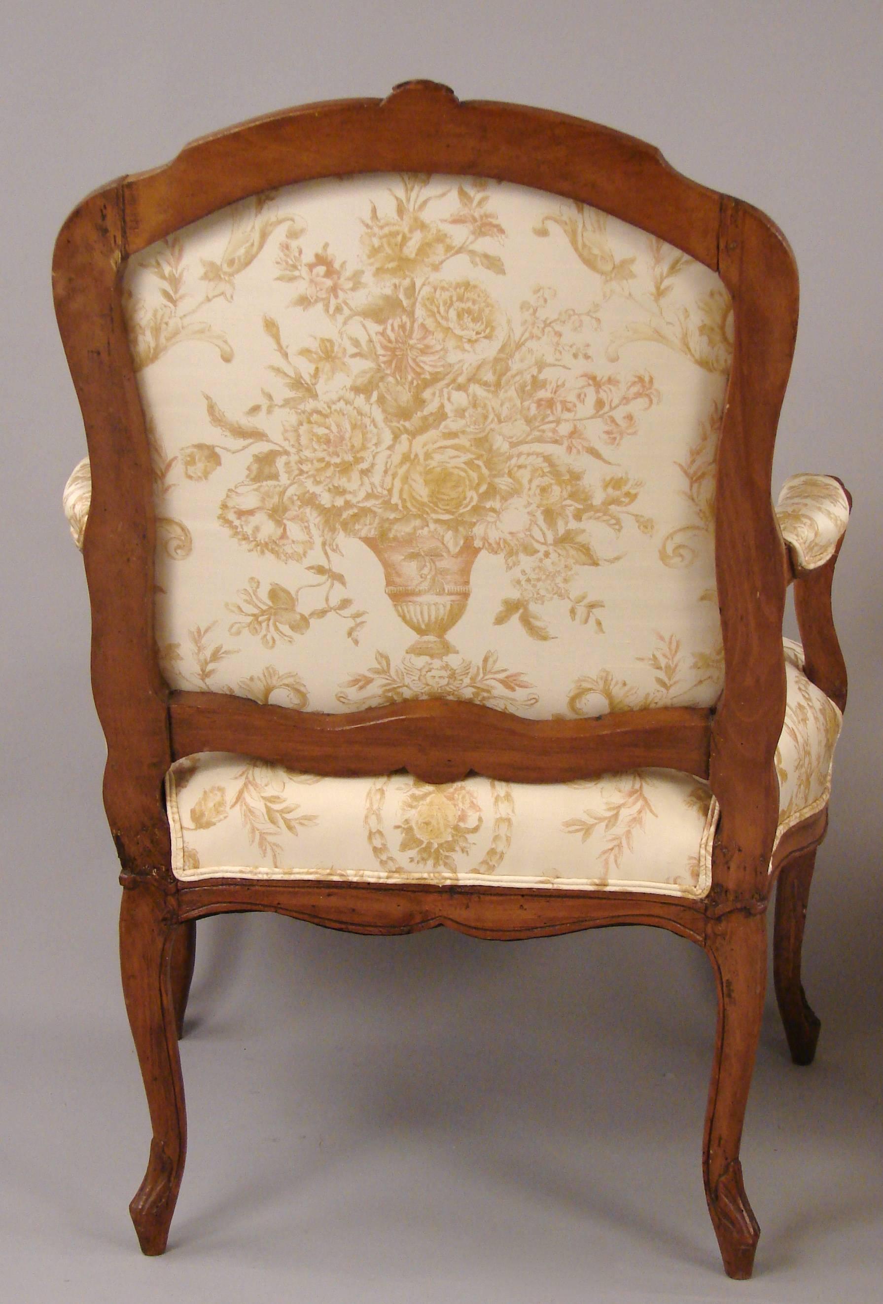 A pretty pair of French Louis XV style walnut armchairs of typical form now upholstered with cream silk floral print, circa 1860 or earlier.