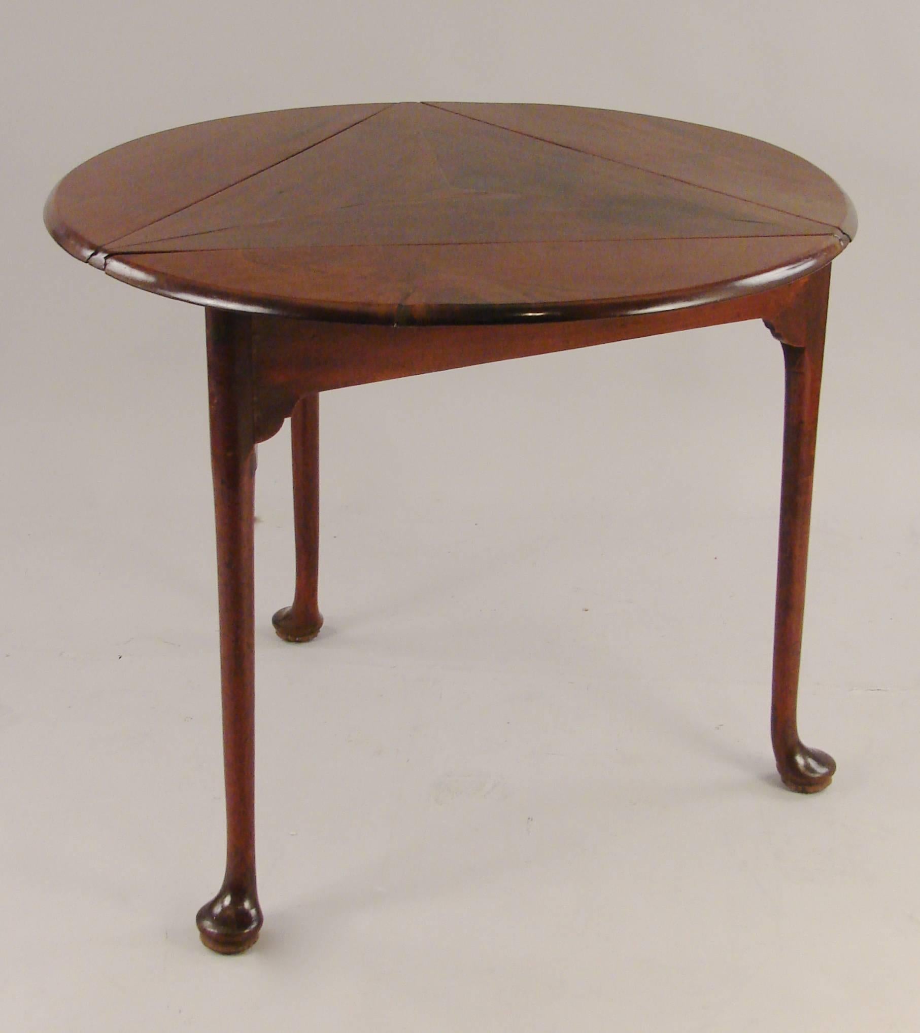 An unusual George II mahogany drop-leaf table, the triangular top revolves to form a round table, supported on cabriole legs ending in pad feet, circa 1760.