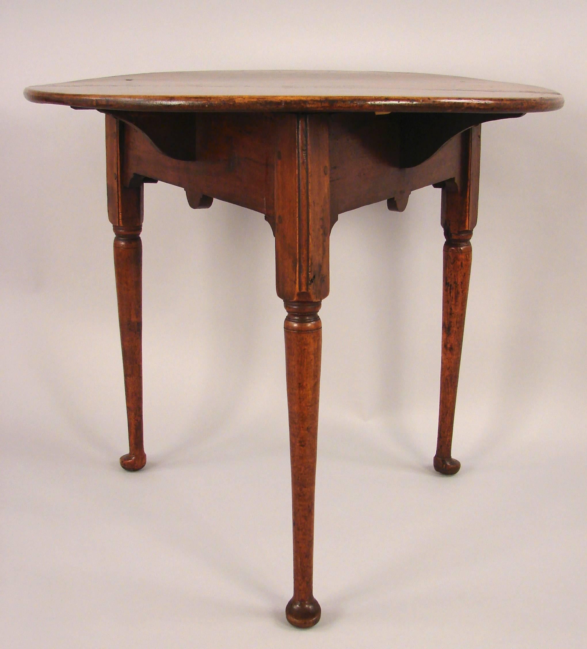 A George II walnut tavern table, the overhanging circular top supported on turned legs ending in pad feet, circa 1760.