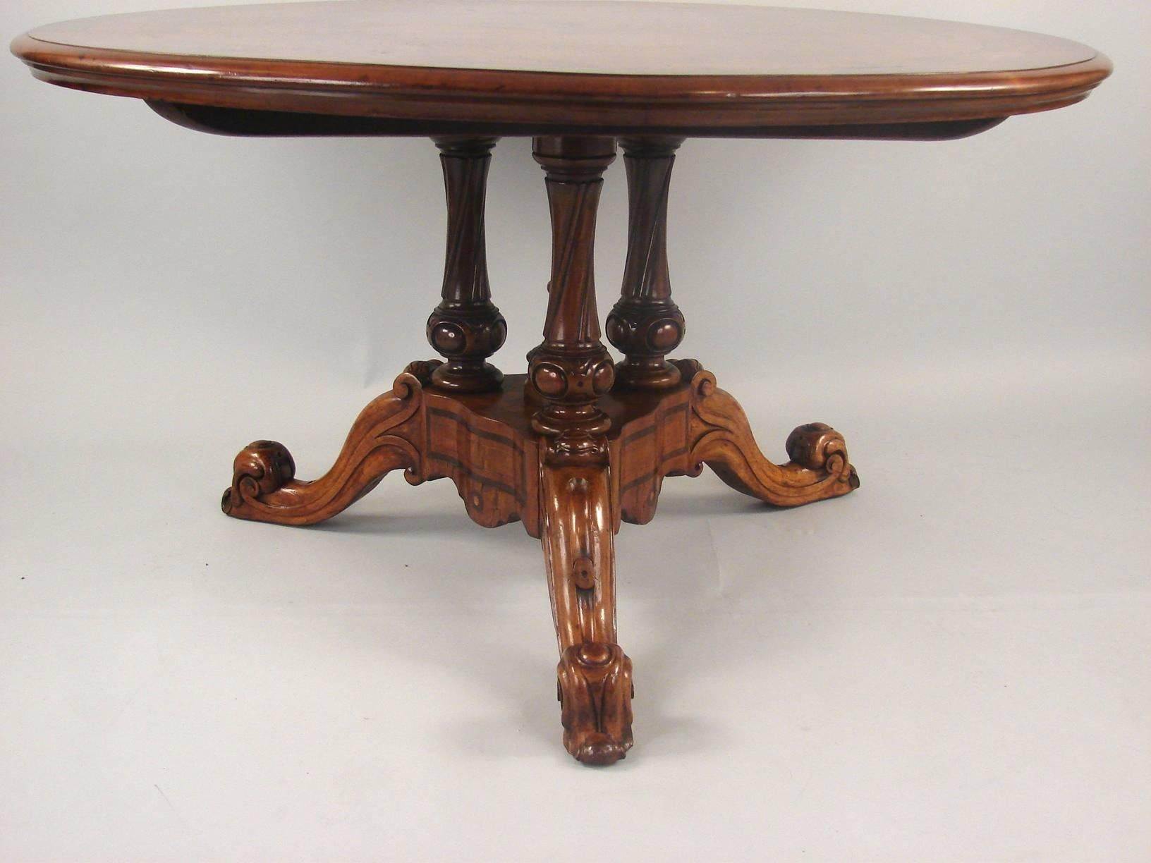 A good quality English walnut center table, the top with figured contrasting burl inlays and a crossbanded edge, supported on three twist carved standards terminating in a tripod base with upturned scroll feet, circa 1860.