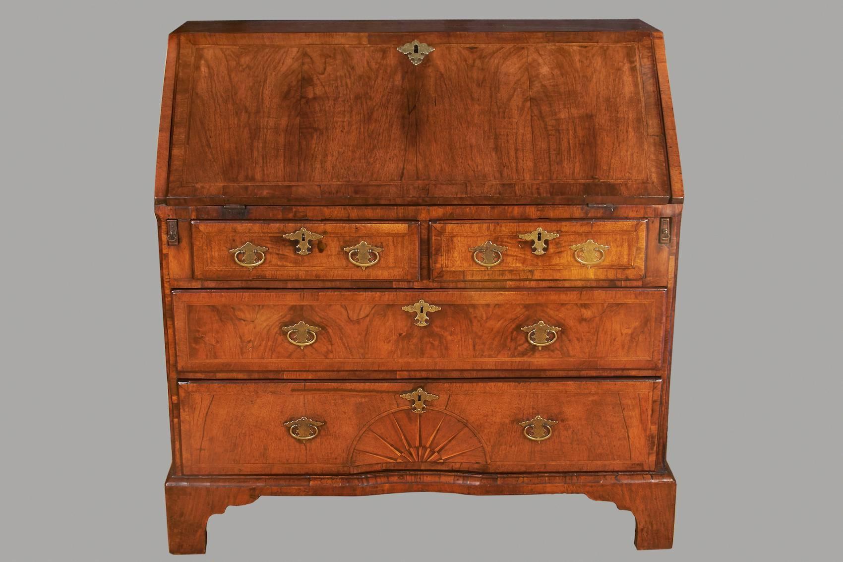 A fine George I period figured walnut bureau, the crossbanded chevron inlaid fall concealing a fitted interior, above two short and two long similarly inlaid and banded drawers, the bottom drawer with concave sunburst inlay, all supported on