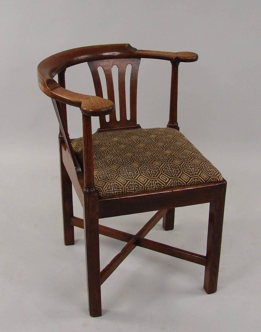 An English oak George III period corner chair of simple form with an X-stretcher and drop-in seat, newly upholstered in elegant black and cream textured silk geometric fabric, circa 1770.