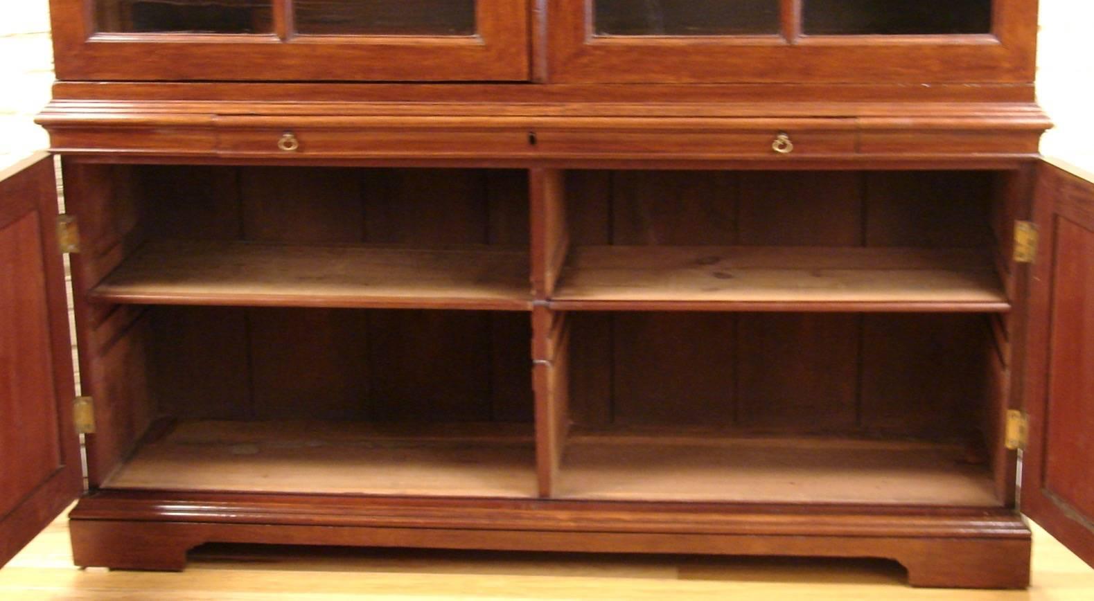 A handsome and substantial scale English George III mahogany bookcase cabinet, the upper stage with two large six-panel glazed cabinet doors, each concealing two adjustable shelves, above a single long drawer over two cabinet doors with interior