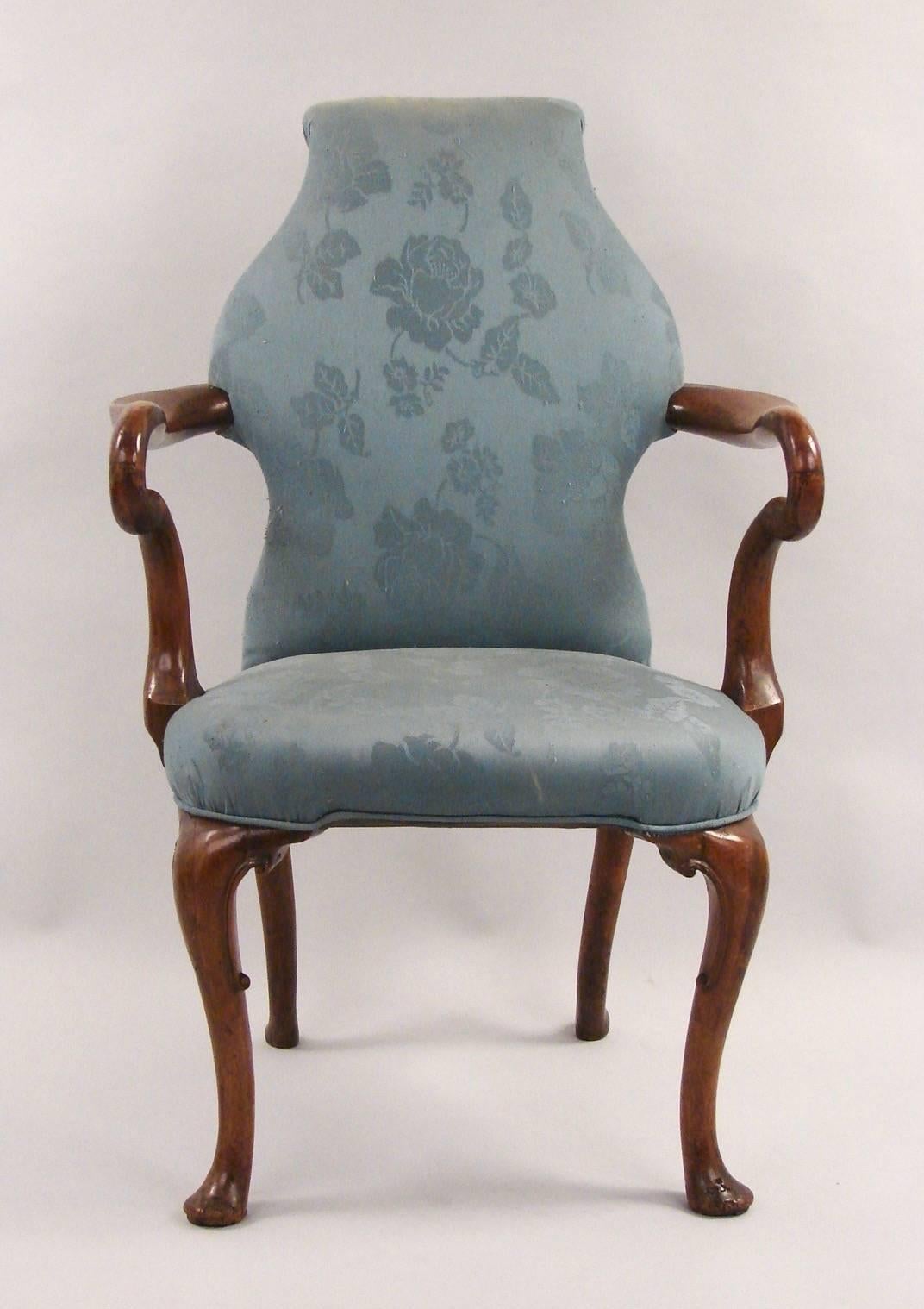 A pair of English George II style walnut armchairs upholstered in blue damask, the shaped back with a scrolled top supporting shepherd's crook arms terminating in a curved seat supported on cabriole legs ending in pad feet.