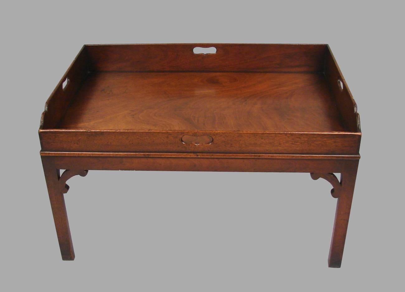A Regency mahogany butler's tray, the well-figured top with four cut-out handles, the front edge lower than the sides, now mounted on a custom mahogany stand with Chippendale-style corner brackets tray, circa 1820.