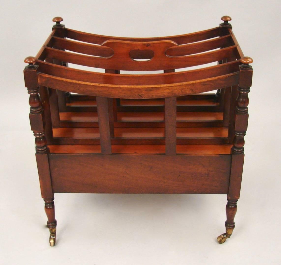 A Regency period mahogany canterbury with carrying handle, the curved four sections divides over a single drawer, supported on turned legs ending in original brass casters. Attractive warm color, circa 1825.