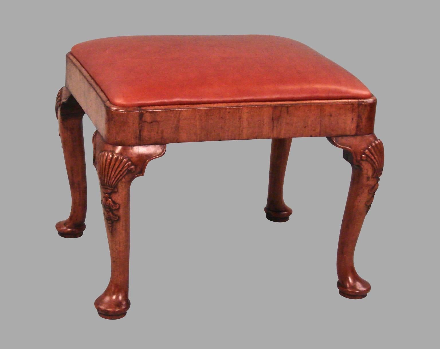 An English George II style walnut veneered stool, the cabriole legs with shell carved knees ending in bell flowers and terminating in pad feet, 19th century.