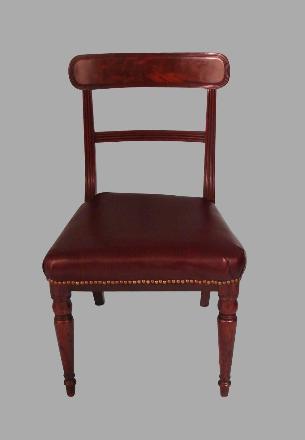 A comfortable and sturdy set of six Regency period side chairs each with a well-figured mahogany back splat supported by reeded stiles, the seats upholstered in claret hide with nailhead trim all supported on turned legs, circa 1820.