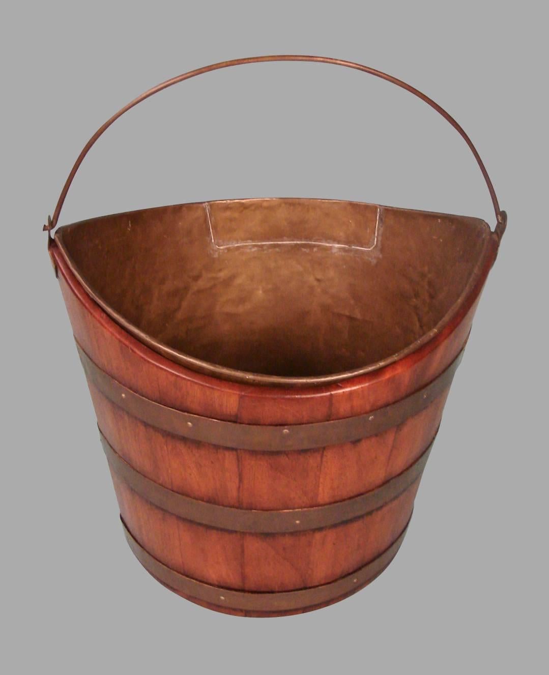 A Regency period mahogany brass-bound peat bucket, the coopered tapering body of navette form complete with a brass liner and handle, circa 1820.