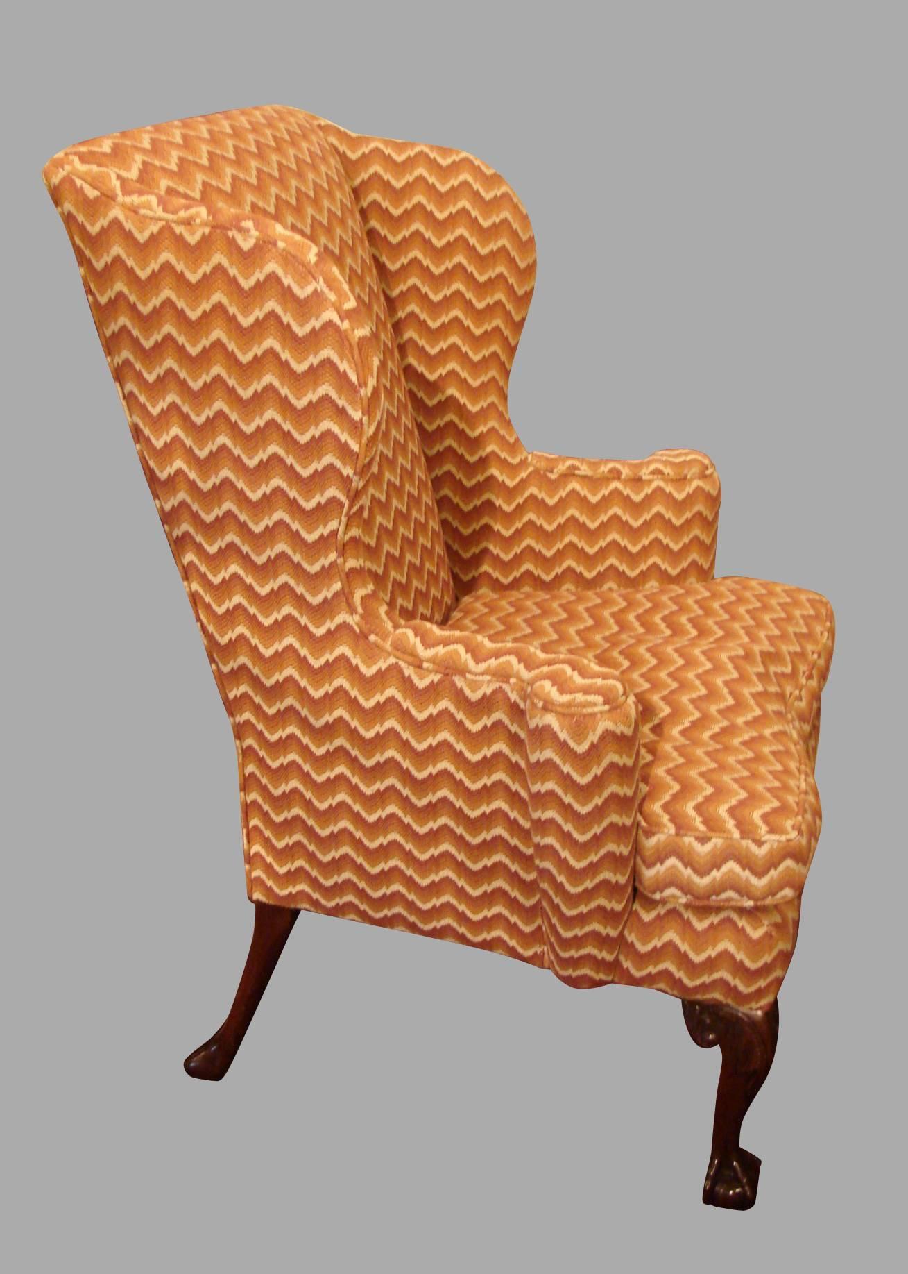 A George III style mahogany wingback armchair, the front short cabriole legs with carved knees ending in ball and claw feet, the rear legs of simple down swept form. This very comfortable bench made chair was upholstered by Fitzgerald, San