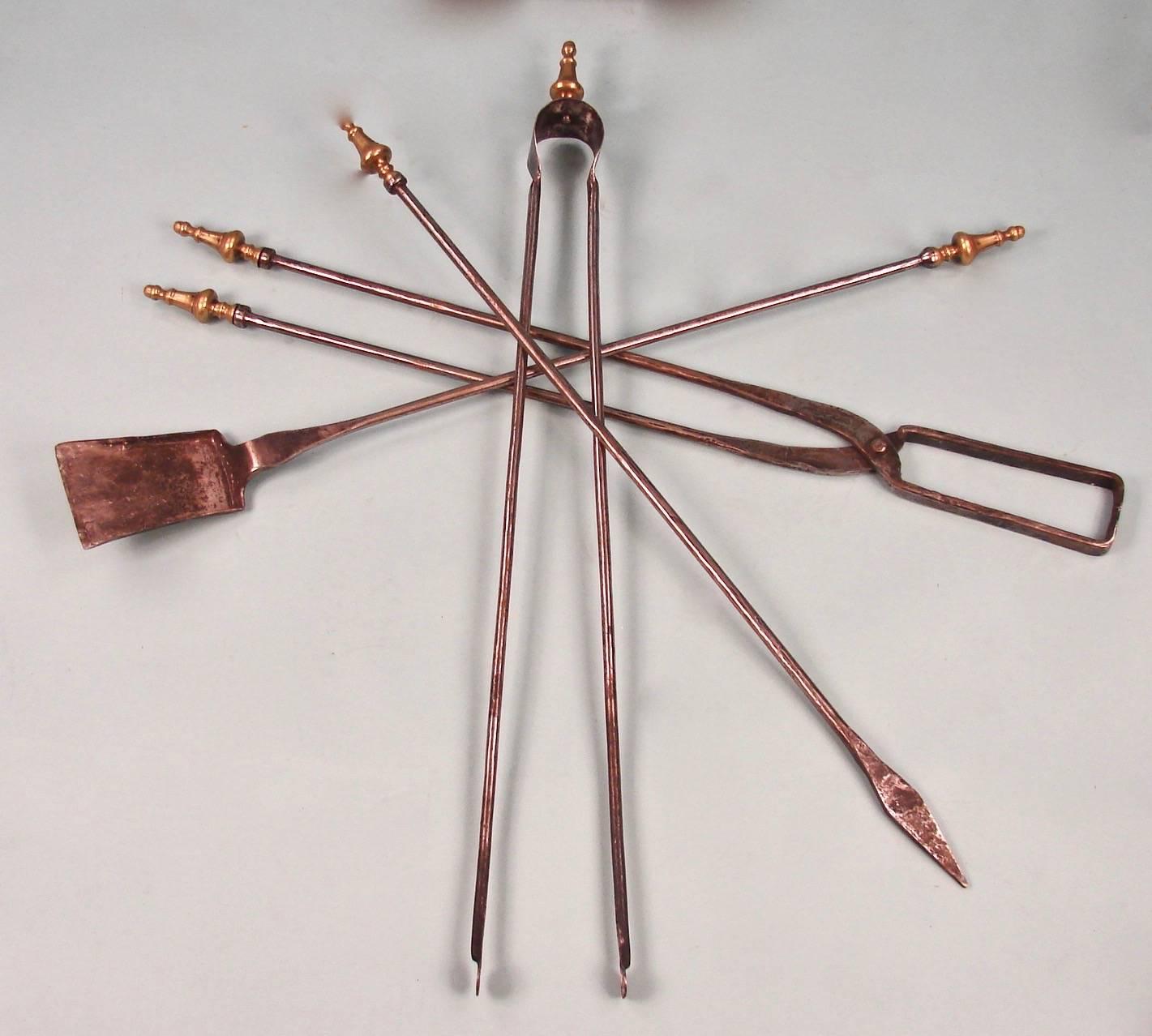 A wonderful hand-wrought oversize set of fire tools with a matching stand, each piece with a brass finial, consisting of a tongs, shovel. Poker and log grabber hand made with a matching stand, 20th century.