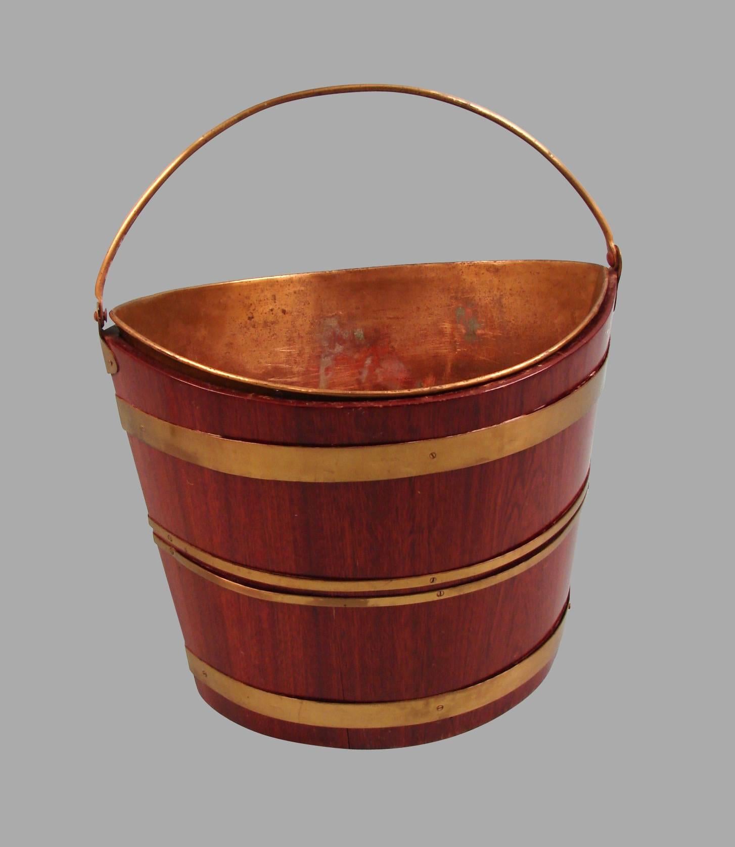 An English Regency period mahogany navette form brass-bound peat bucket with four brass bands and a brass liner, circa 1820.