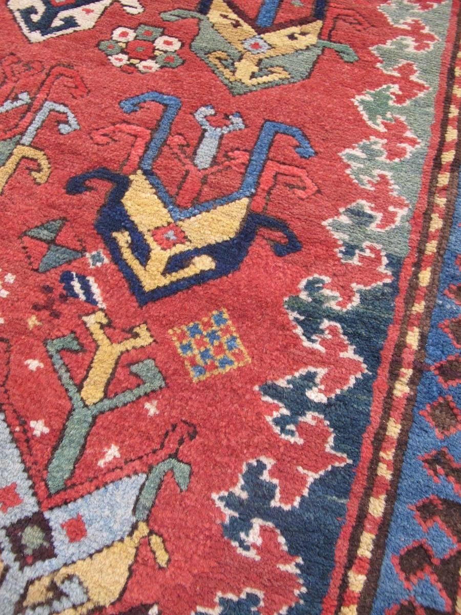 Caucasian rugs are renowned for their boldness of color and design. This thick-piled Gendje long rug paints large colorful shield-palmettes against a saturated red madder ground. Such palmettes are more typically found in finer Shrivan weavings and