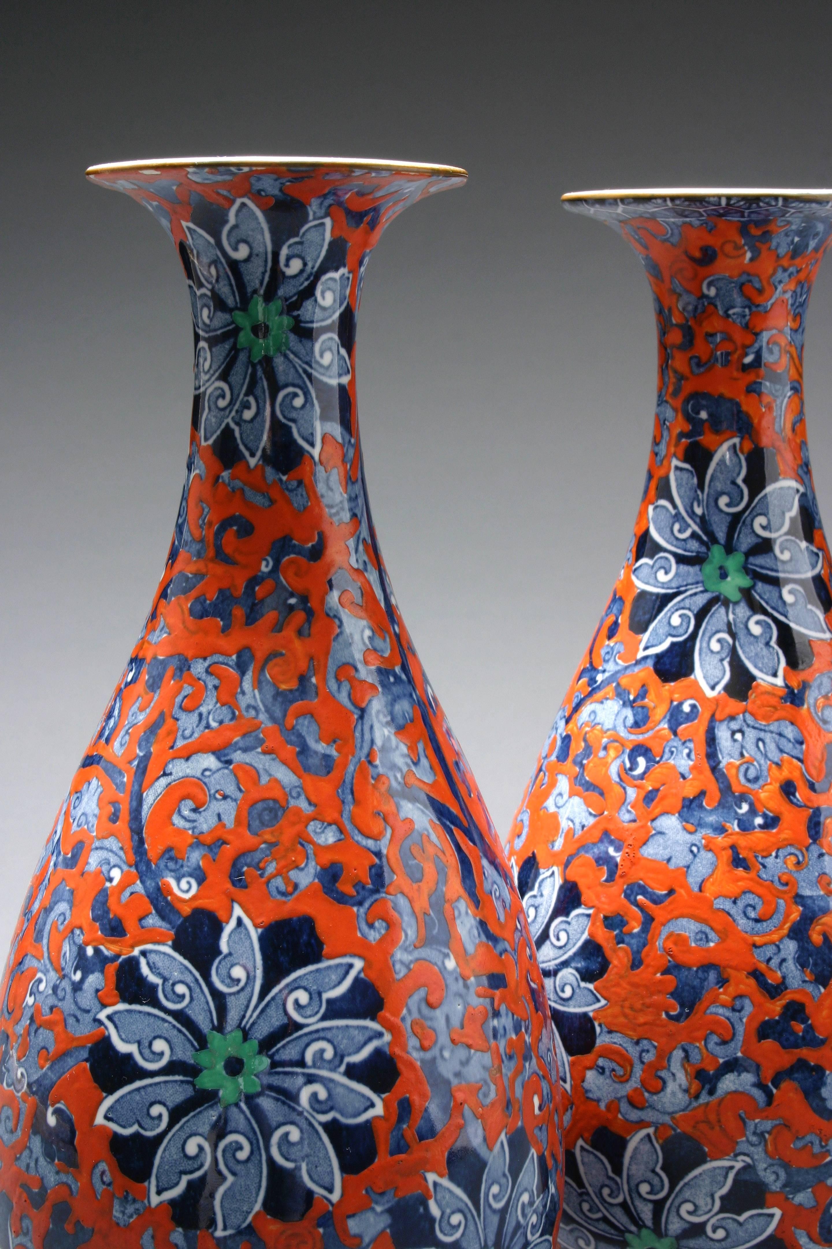 Very handsome vases with a beautiful polychrome design. Each of a slender bottle form with flared lip, decorated with exotic green and blue flowers issuing scolling vines, with a red overglaze. Marked: Chung Ro No. 631664 L & Co