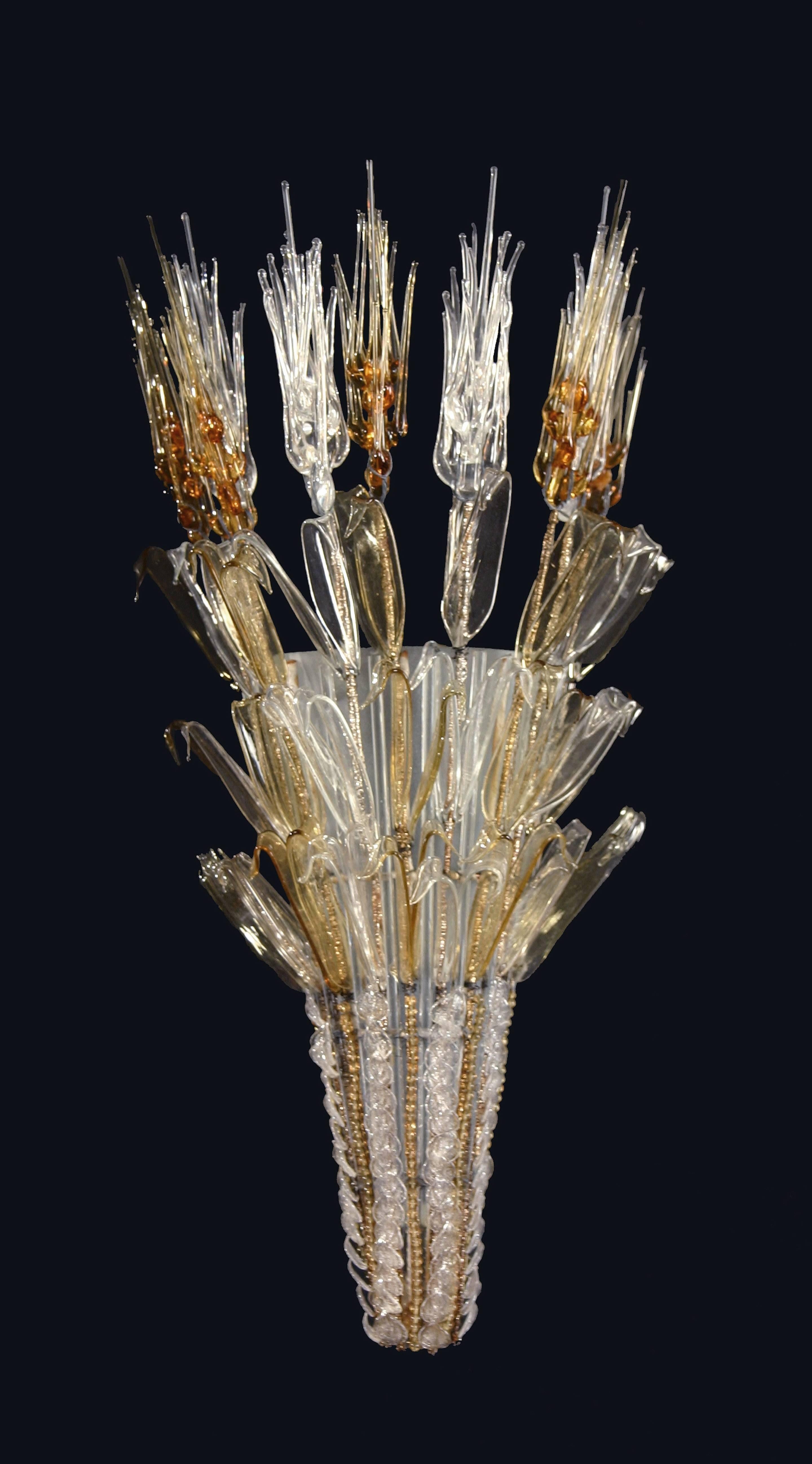 Each vase-form sconce crowned by alternating yellow and clear glass leafy sheaths of grain, above small petal like leaves, over a demilune of frosted glass.  Not electrified.

Mobilier et Decoration, Number 5, 1954, “Le Trente Huitieme Salon des