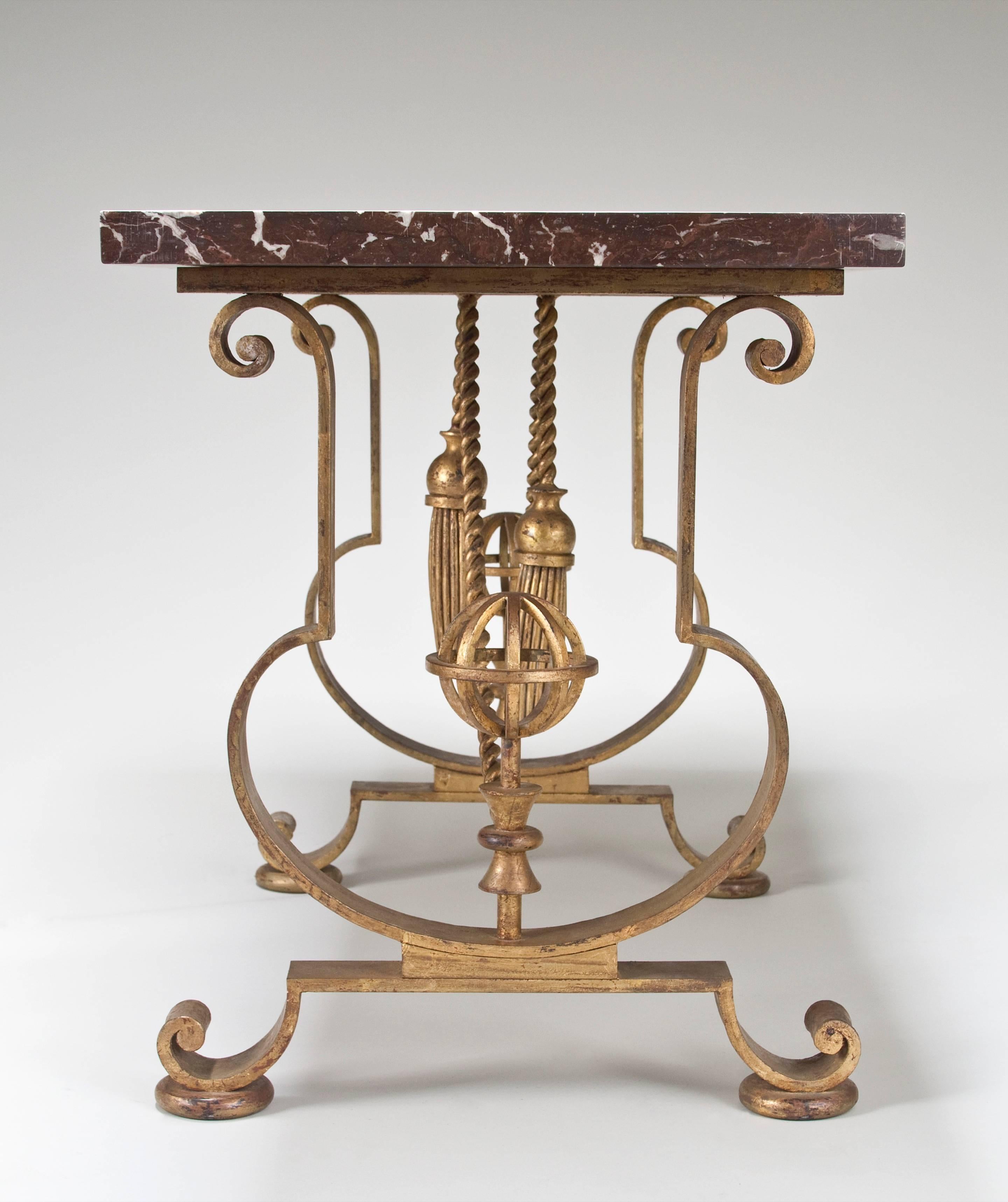 The rectangular rosso levanto marble top, above scrolled, lyre-shaped supports enclosing two astrolabes on hourglass plinths, joined by two ropes issuing draped tassels, the whole on scrolled legs above rounded disk feet. 

A Certificate of