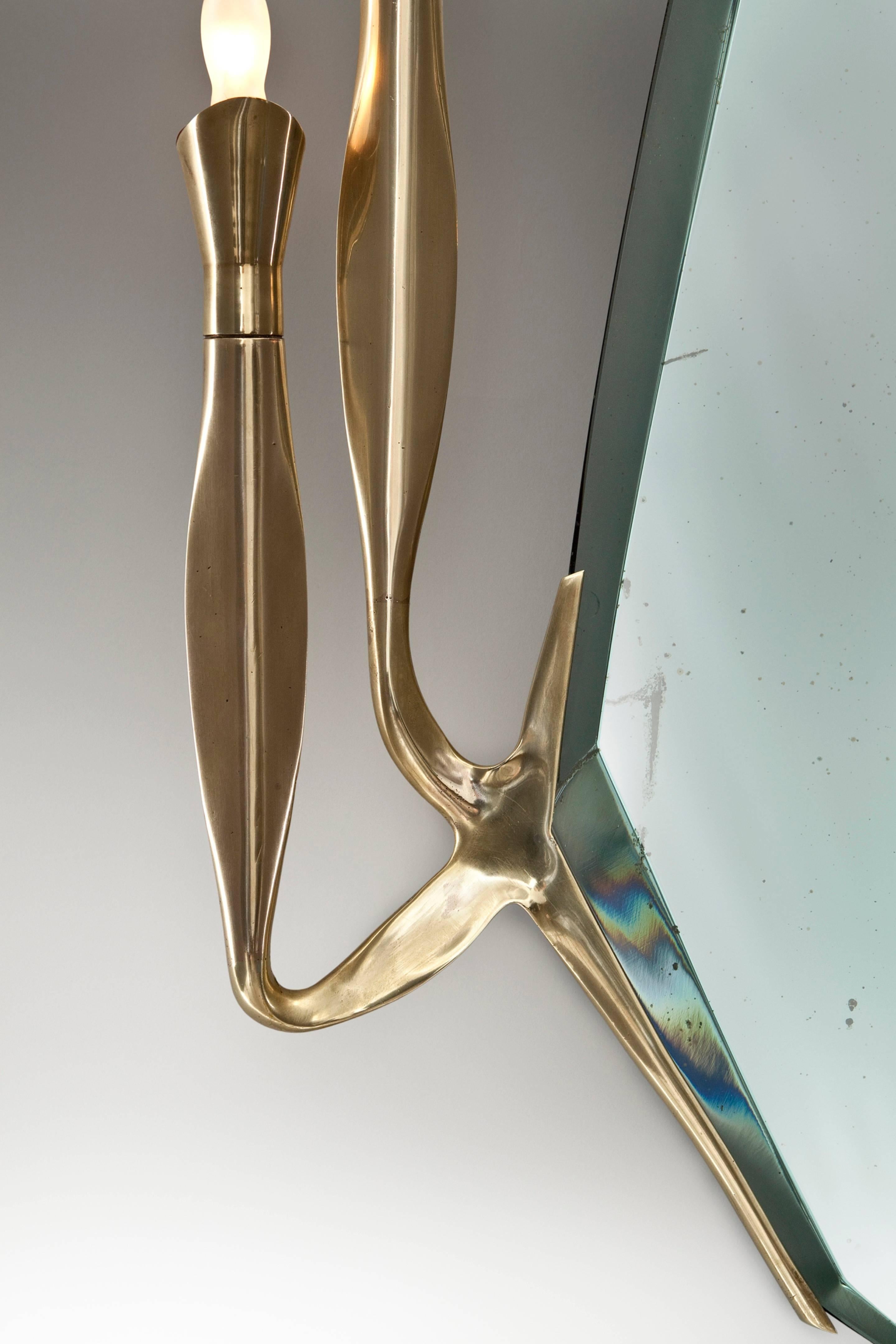 One of the sought after and hardest to find Fontana mirrors. The cartouch-shaped aquamarine-tinted mirror plate with an angular bevel, issuing four curvaceous upright brass arms, each arm with a single light holder.

For related examples, see