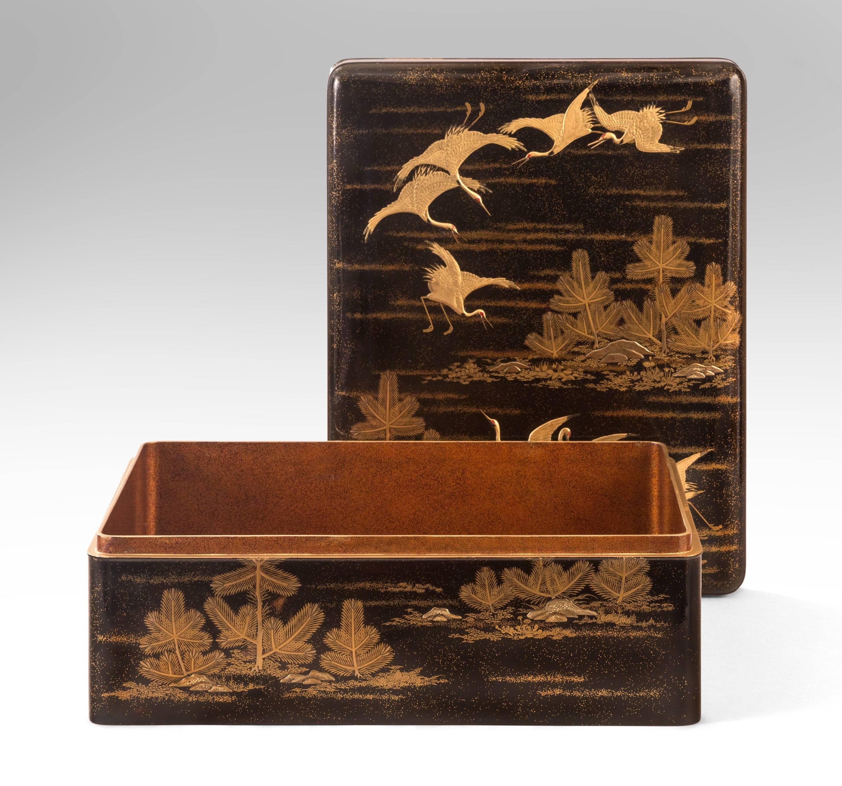 A Large Japanese Gold Lacquer Box (Bunko) Depicting Cranes and Pine Trees
A gorgeous box of high quality with a beautiful scene of canes amongst pines.
Of rectangular form with rounded corners, the top and sides depicting a flock of cranes in