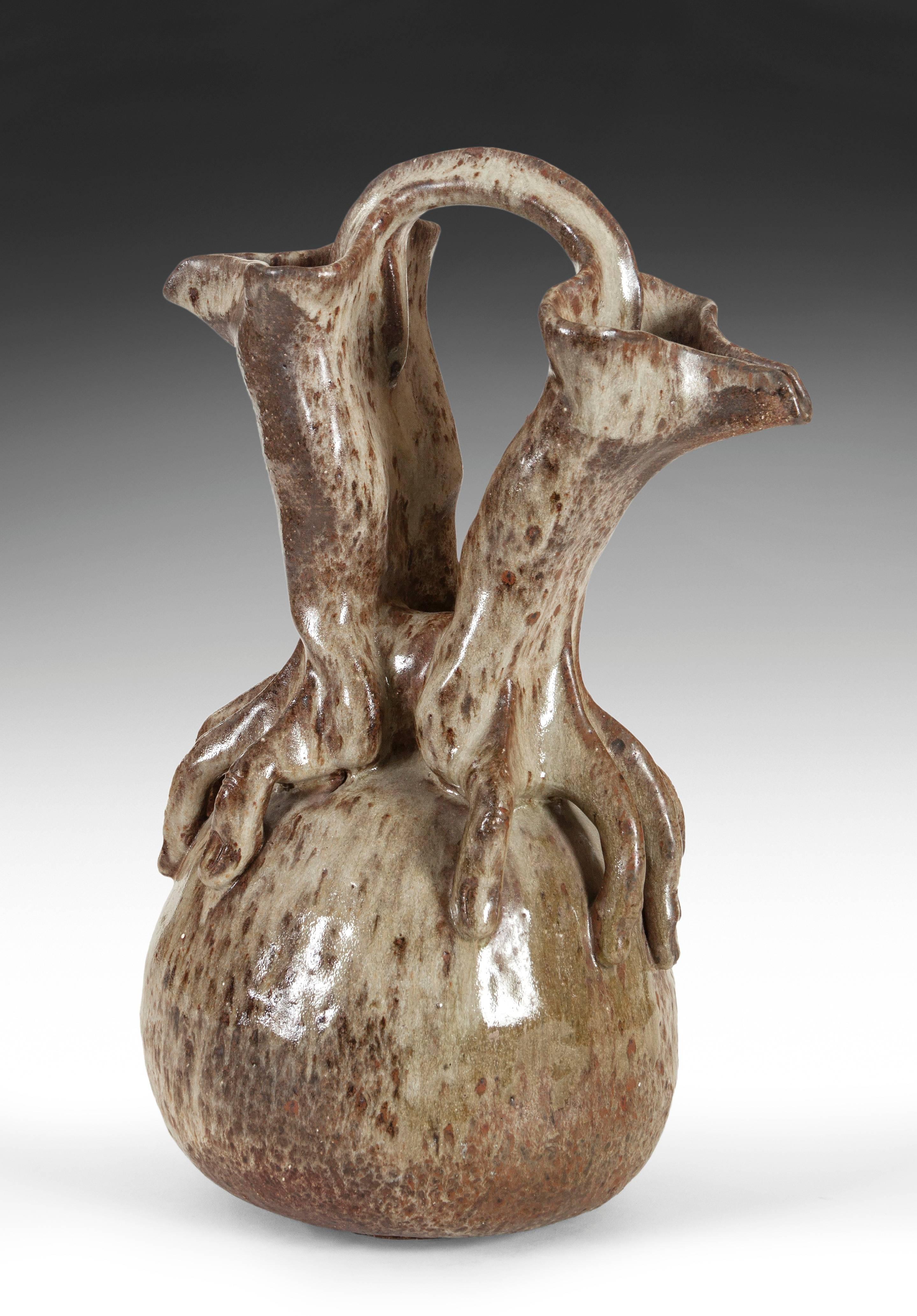 The surreal composition expertly executed and handsomely glazed. The two hands placed atop a rounded-form, each arm terminating in a folded spout joined to a sinuous handle. Illegibly signed on the base.