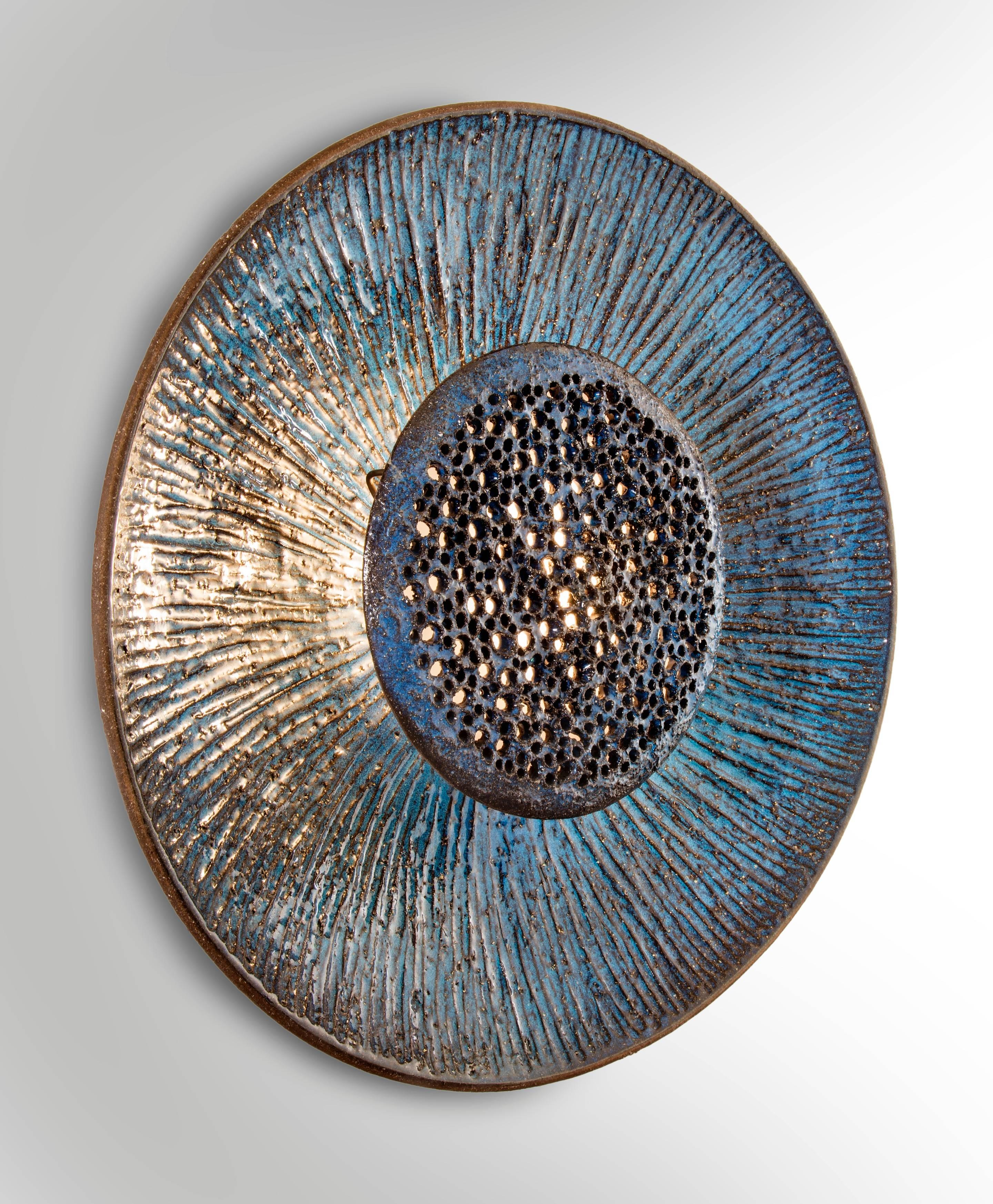 The scored bowl-shaped reflector centering a perforated lotus diffuser, the whole in a richly variegated blue glaze.