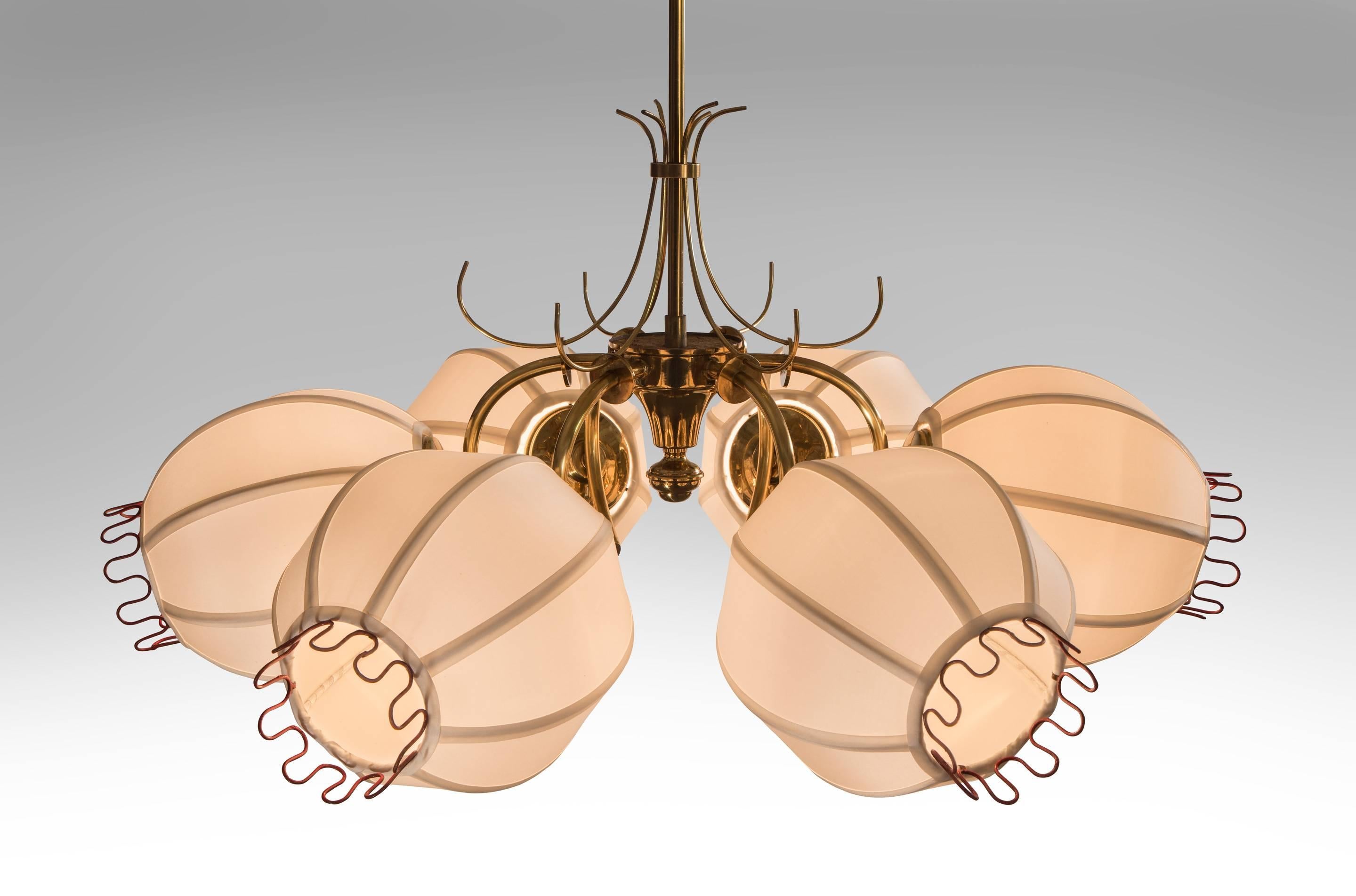 An imaginatively inventive chandelier. The brass canopy, above a hanging rod centering a conical body, issuing six c-curved arms, each arm supporting a spherical silk shade terminating with undulating red wire. 

The height is easily adjustable.