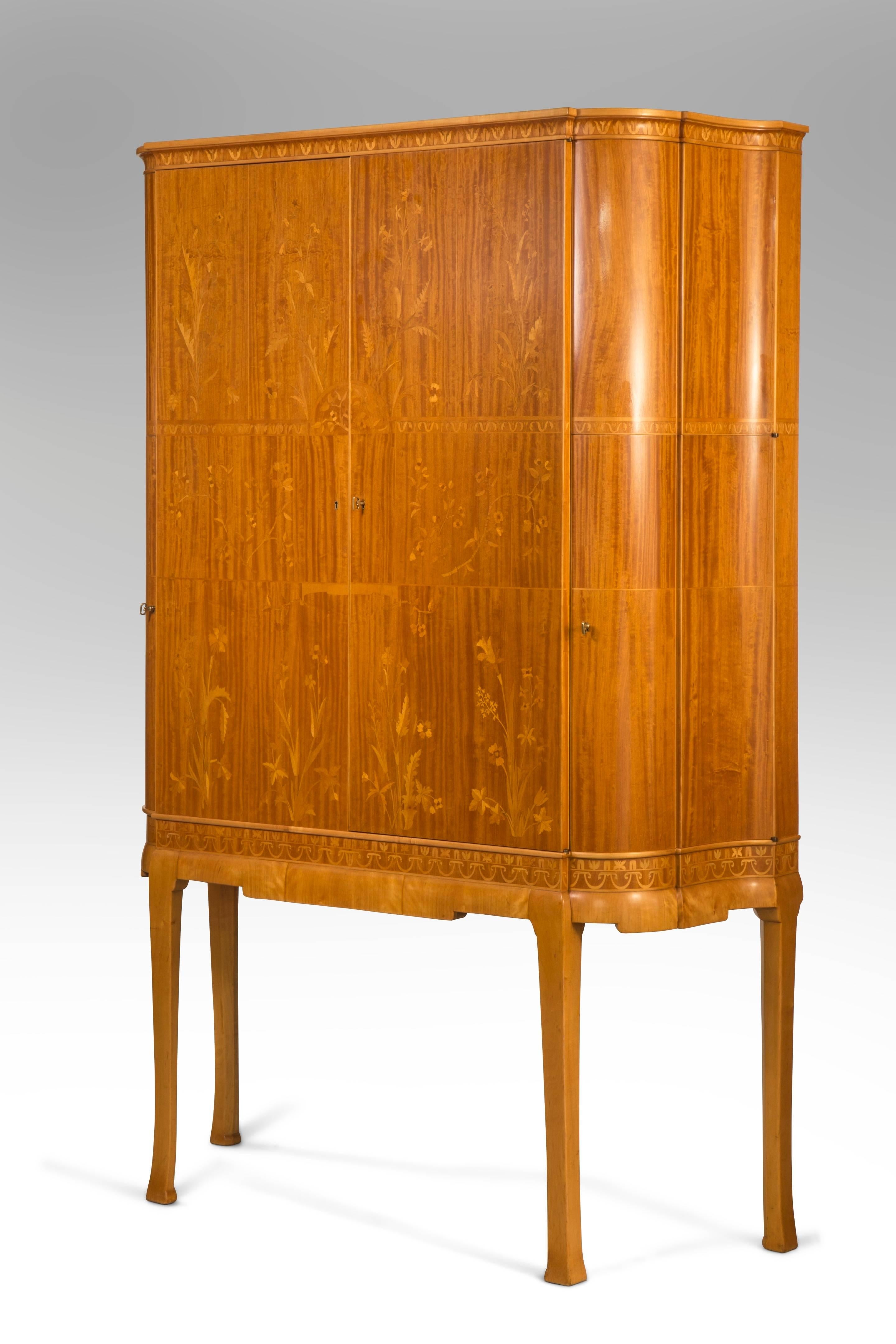 Superb quality, choice materials and very likely a special commission. The molded serpentine top, above a conforming cabinet with two front and two side doors, festooned in individually designed marquetry bouquets, the interior with adjustable