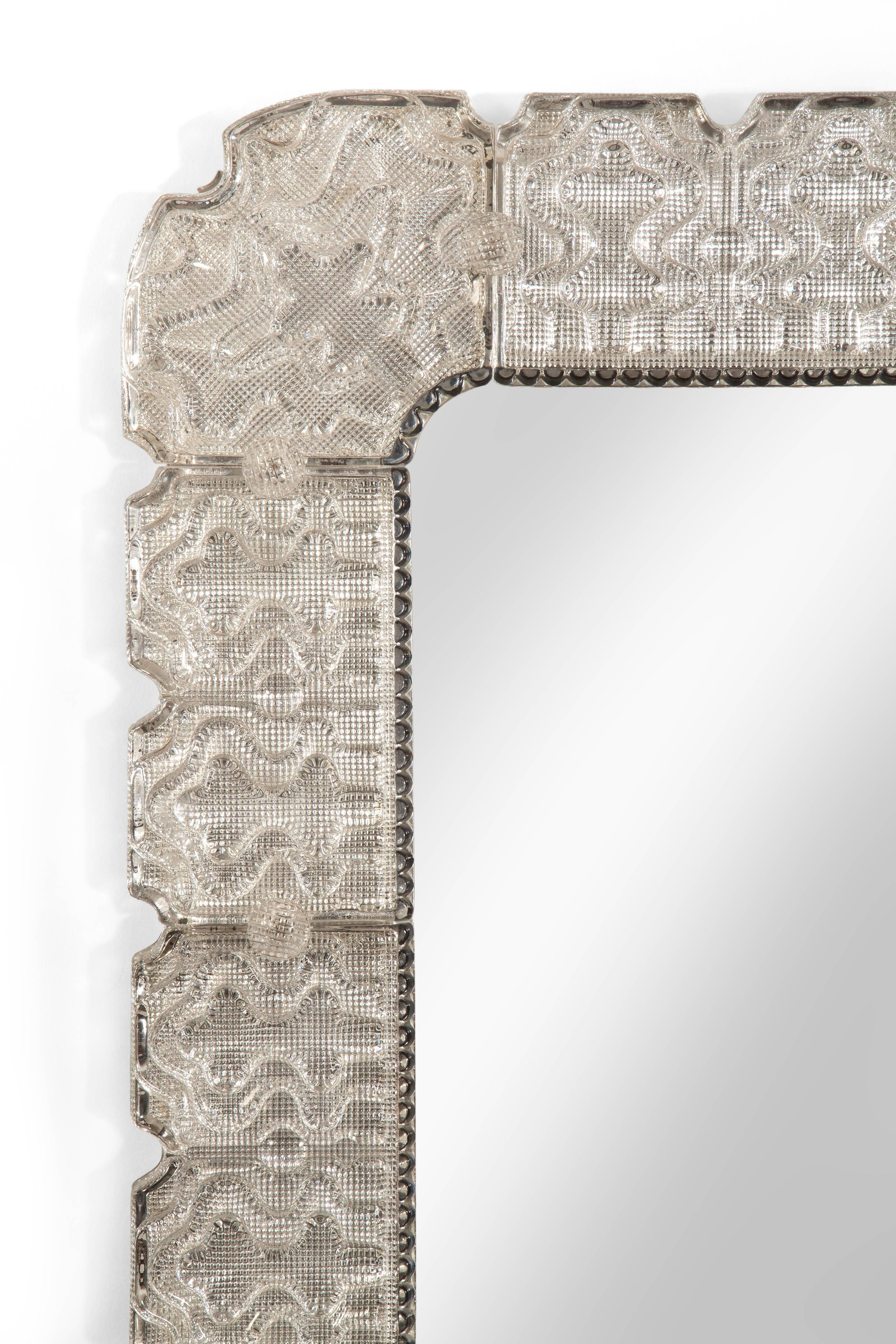 Really beautiful cast glass has an alluring way of responding to light. The rectangular mirror plate with rounded corners and within a glass pearl border, the frame of segmented ice glass attached by glass buttons.

In great overall condition. Ready