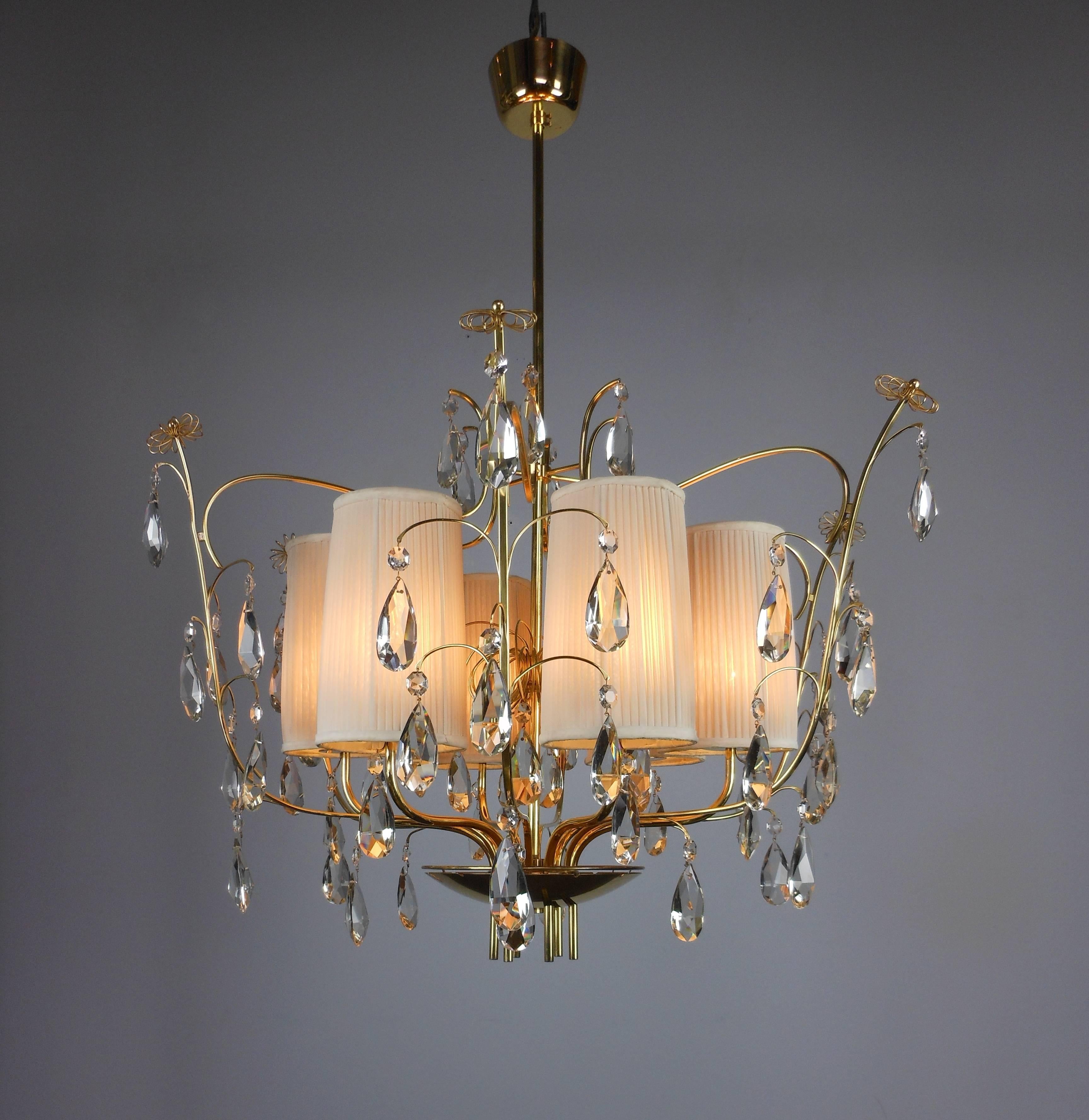 The circular domed canopy above the stem centered with a large spiral and a dish pierced with cylinders, the frame  of S-shape arms supporting lights alternating with bow form arms hung with teardrop crystals and ending in spirals.

Manufactured