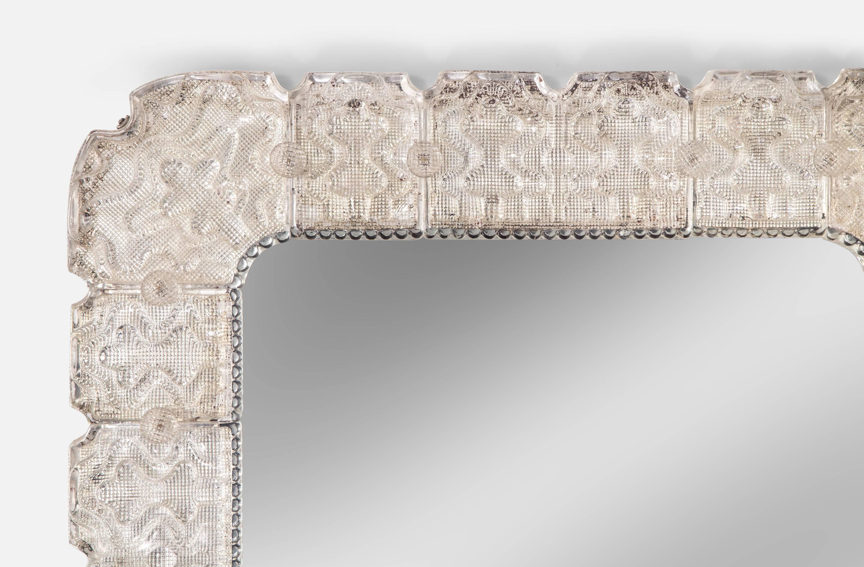 The rectangular mirror plate with rounded corners and within a glass pearl border, the frame of segmented ice glass attached by glass buttons.