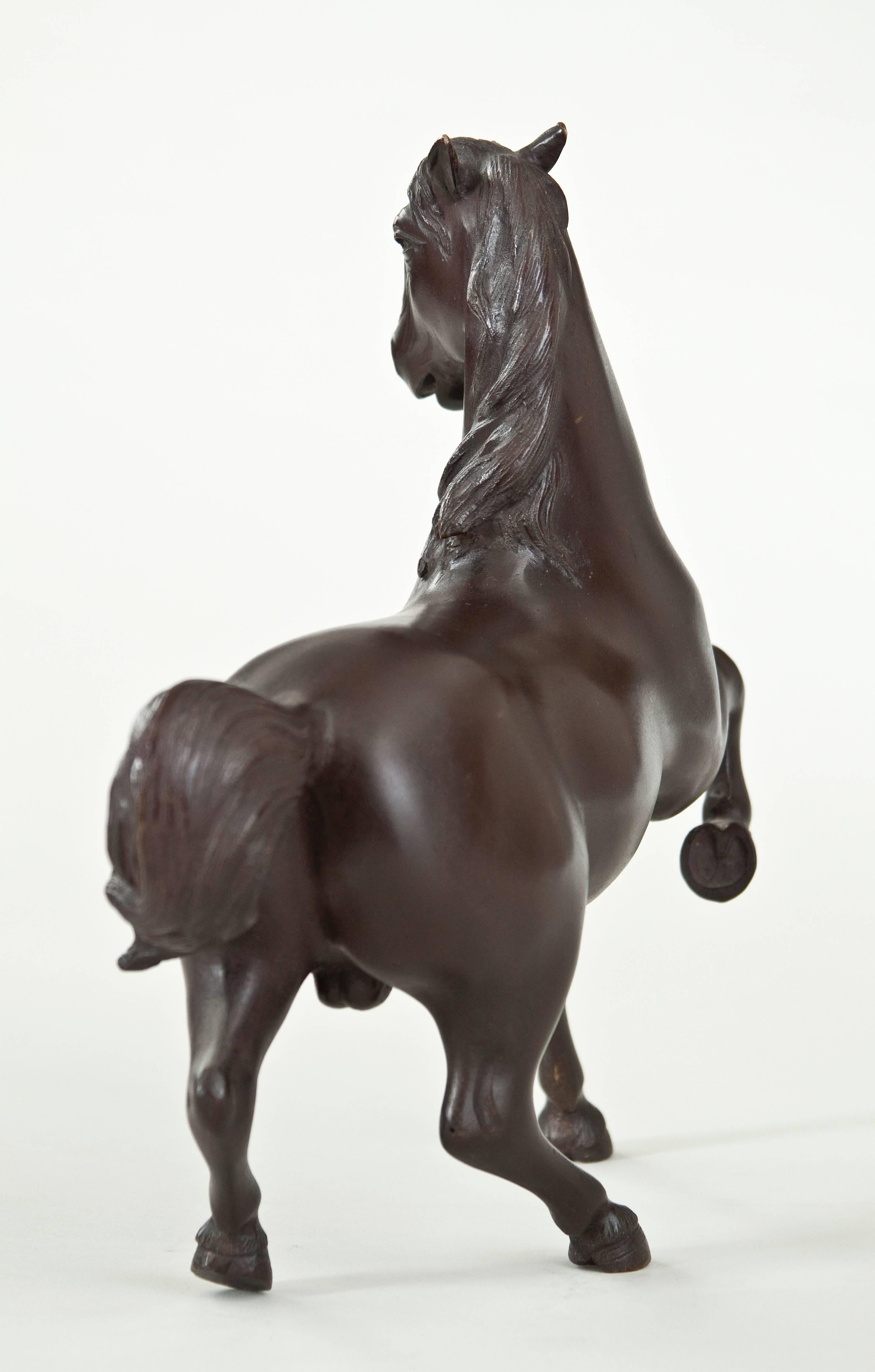 With modeled and incised mane and tail, the dynamic horse with alert ears looking to the left, the front right leg held aloft.

Very good condition with a rich dark patina. A great example of Japanese metal artistry.