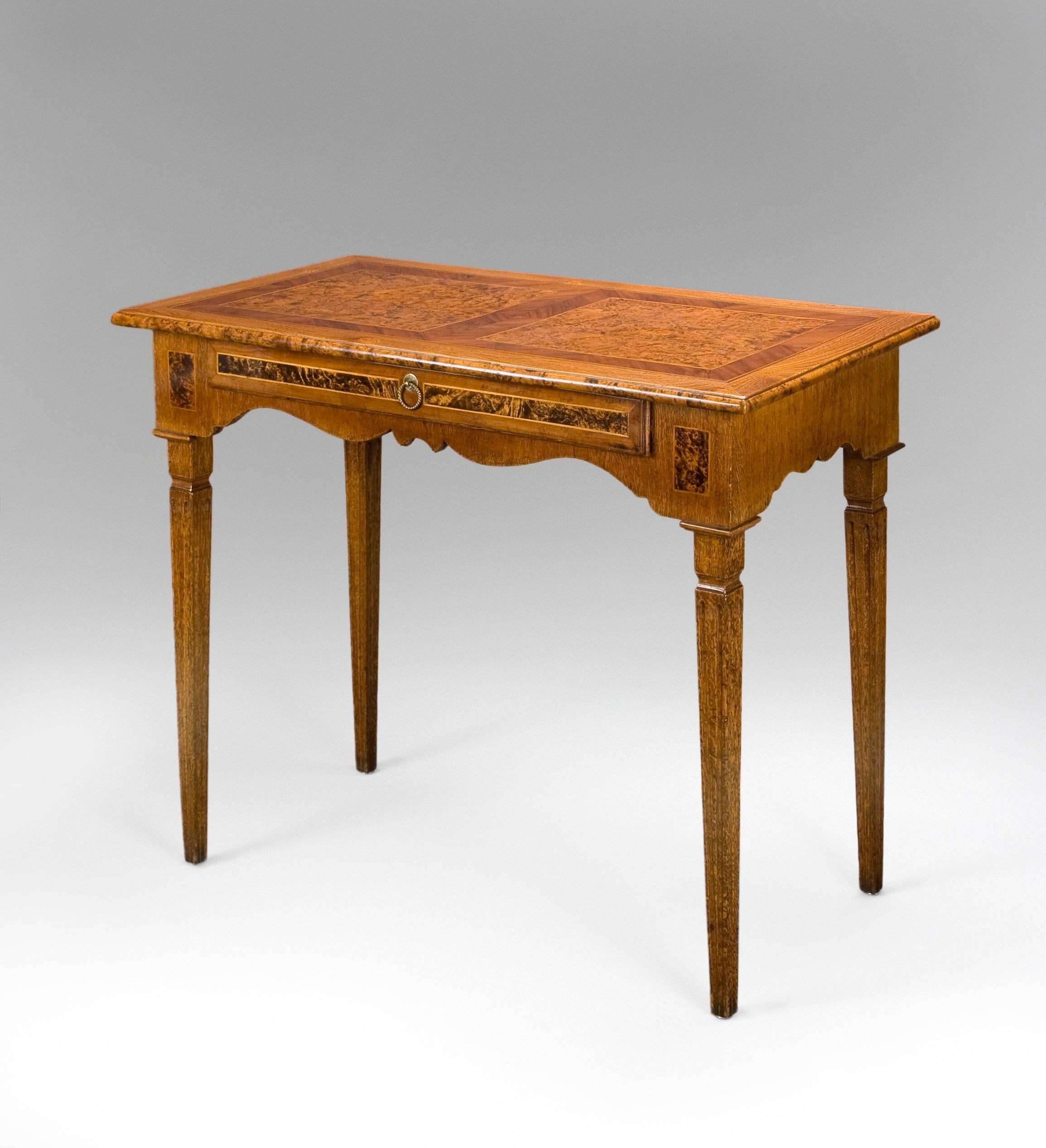 A charming table of choice woods in an attractive pattern. The rectangular top with molded edge and two burlwood panels bordered by fruitwood, above a serpentine frieze containing one drawer, raised on four square fluted, tapering legs.

Very good
